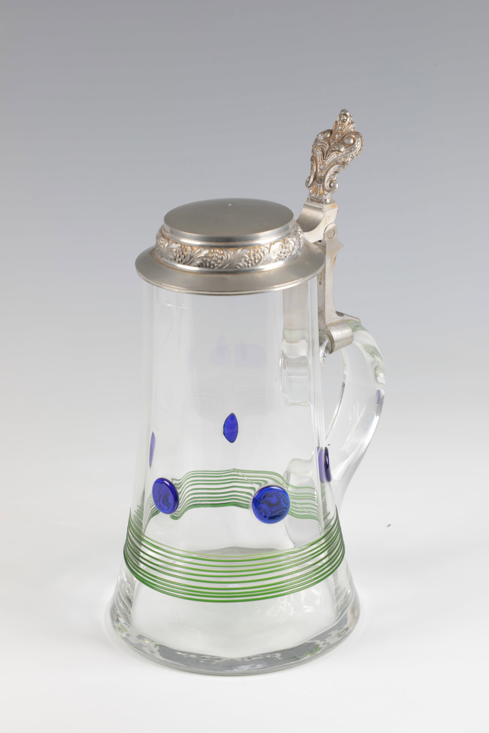 Beer mug ''Harka'': Beer mug ''Harka'' Freiherr v. Poschinger'sche Krystallglasfabrik, Frauenau, c. 1900-05 Colourless, optically blown glass, with melted green threads and blue dots. Tin lid. H. 24.5 cm (incl. pusher).