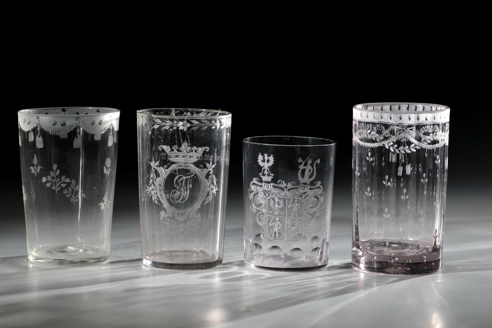 Four Cups: Colorless glass. On the multi-faceted wall a cut, crowned shield with initials ''JF'' and inscription on the back: ''das ist mein besther trunk''. Below the matt lip rim there is a flower garland all