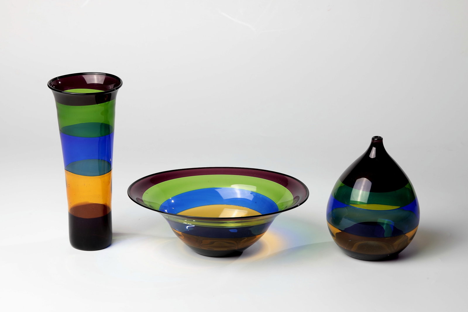 Two vases and a bowl: Two Vases and a Bowl Reinhard Herzog, 1980s Blue, yellow, green and purple striped glass blown in front of the lamp. H. 7.5 - 20.5 cm. Zwei Vasen und eine Schale Reinhard Herzog, 1980er Jahre Vor der