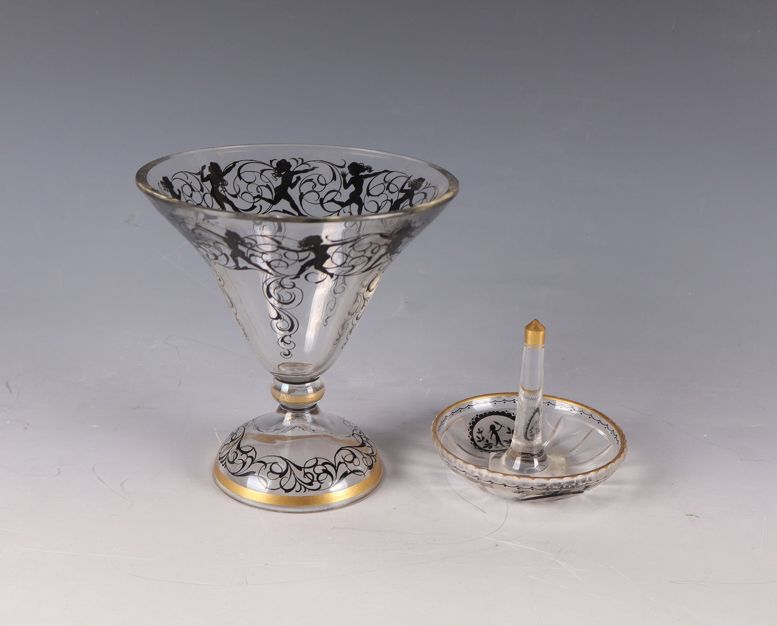 Vase and Ringholder: Vase and Ringholder from the Steinschönau School of Glass, c. 1915 Colourless, partly cut glass with black plumb painting. Figurative decoration all around in silhouette style. Gold-staffed. H.