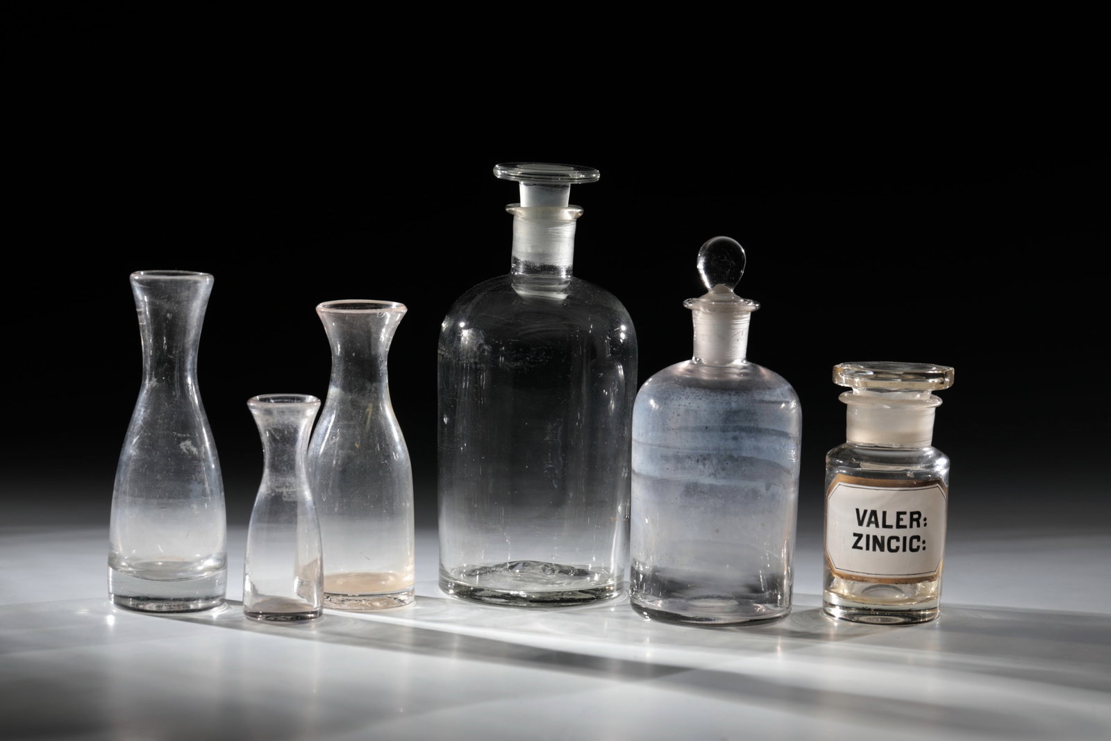 Mixed lot of six apothecary jars: Mixed lot of six apothecary jars 18th / 19th century Three caraffins ais colorless glass with tear-off. club-shaped. Below the spout calibration marks: '' 1/8 or 0.1 l''. One bumped. H. 9.5 - 14.5 cm
