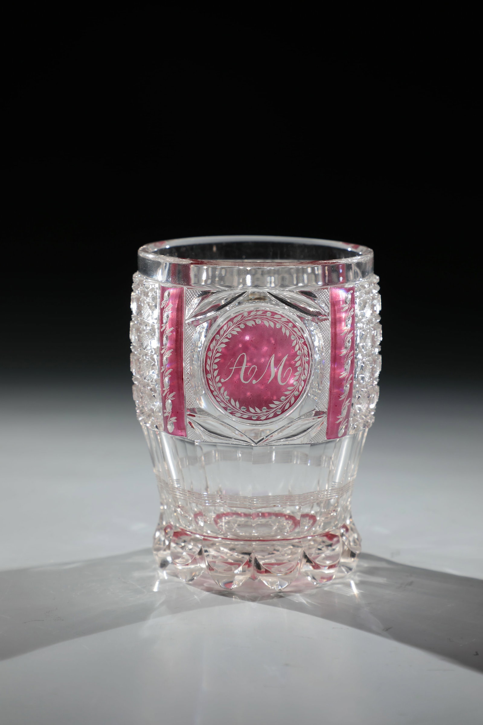 Monogram Mug: Beaker with monogram Gräflich Harrach'sche Glashütte, Neuwelt, c. 1840 Colourless, partly pink glazed glass with rich cut decoration. Front round medallion with engraved monogram ''AM''. H.