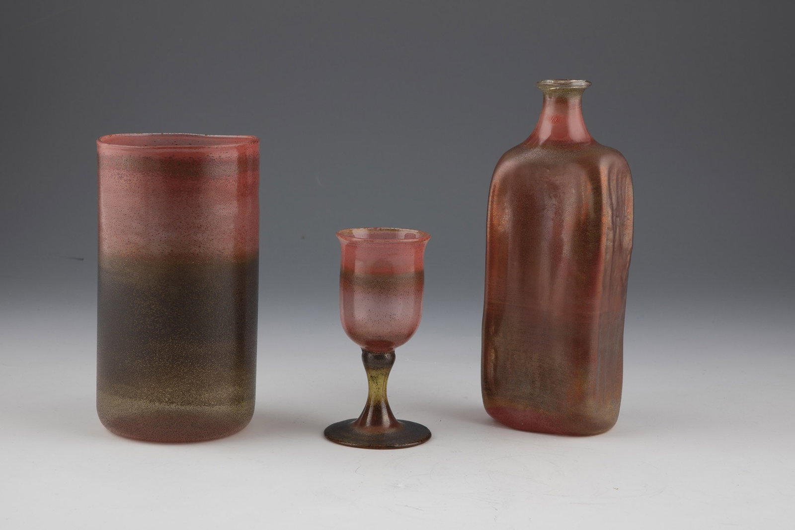 Bottle, vase and small foot cup: Bottle, vase and small foot cup probably Kurt Wallstab Colourless glass with coloured powder inclusions and melted metal compounds. H. 12 - 20.5 cm. Flasche, Vase und kleiner Fußbecher wohl Kurt