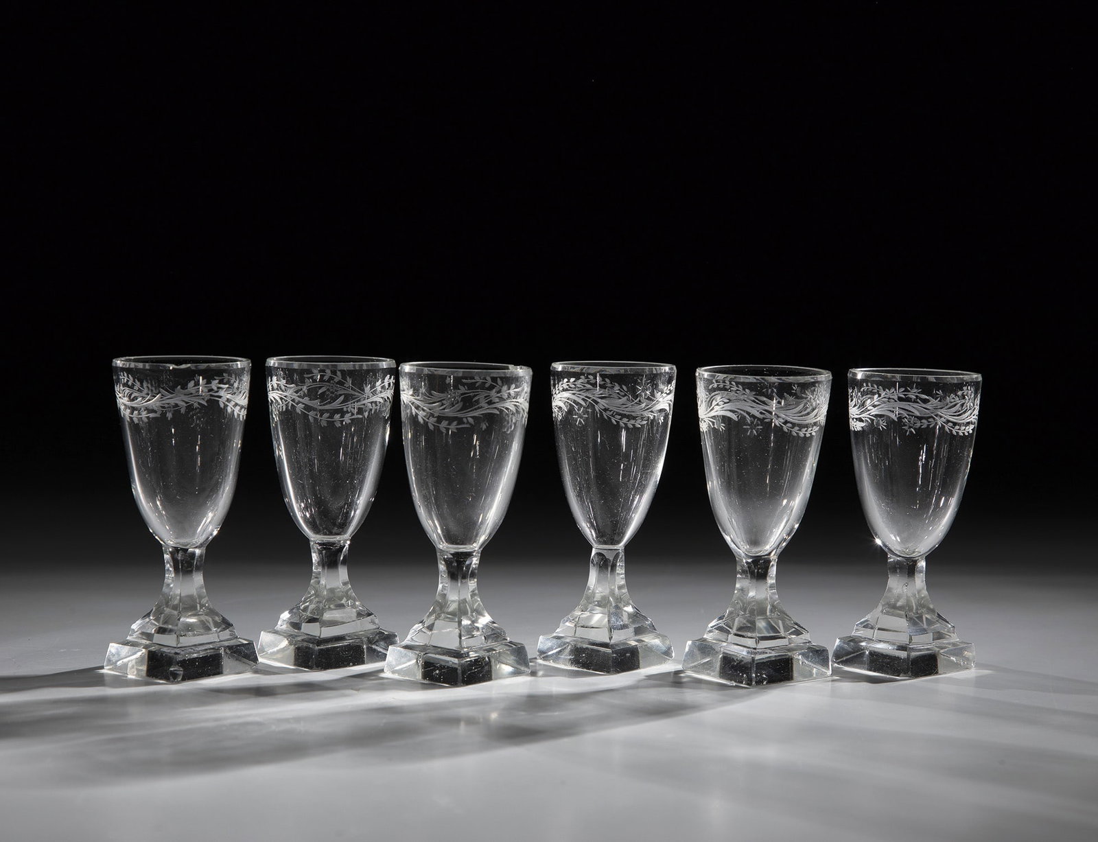Set of six liqueur glasses: Set of Six Liqueur Glasses circa 1820 Colorless Glass. Square plinth. Bell-shaped cuppa with circumferential, finely cut leaf and flower garland. Partly bumped. H. 9 cm Satz von sechs