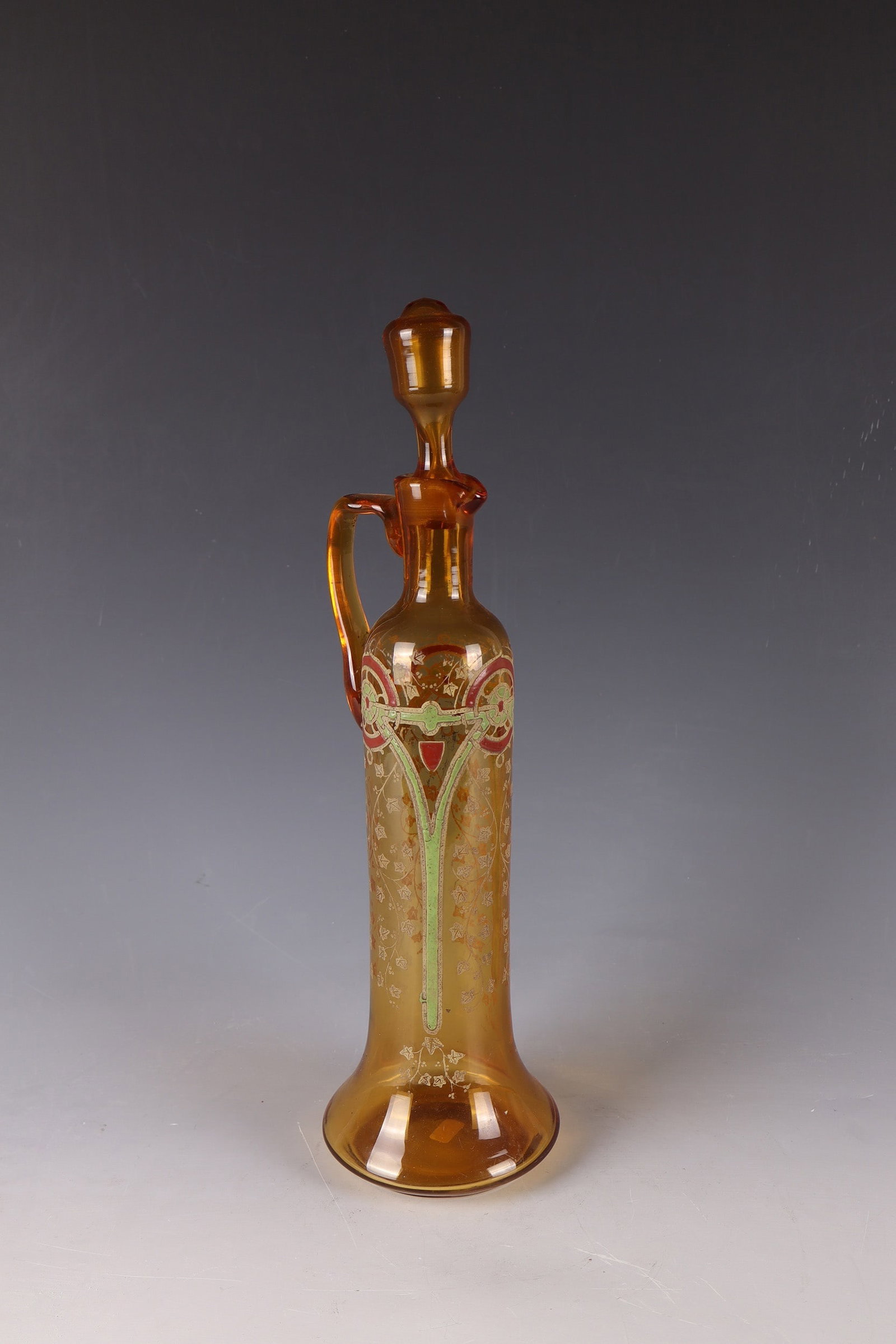 Carafe with stopper: Carafe with stopper Wohl Böhmen, c. 1920/30 Amber-coloured glass with ornamental decoration of polychrome opaque enamel and ochre-coloured reprint pattern. Handle applied on the side and stopper