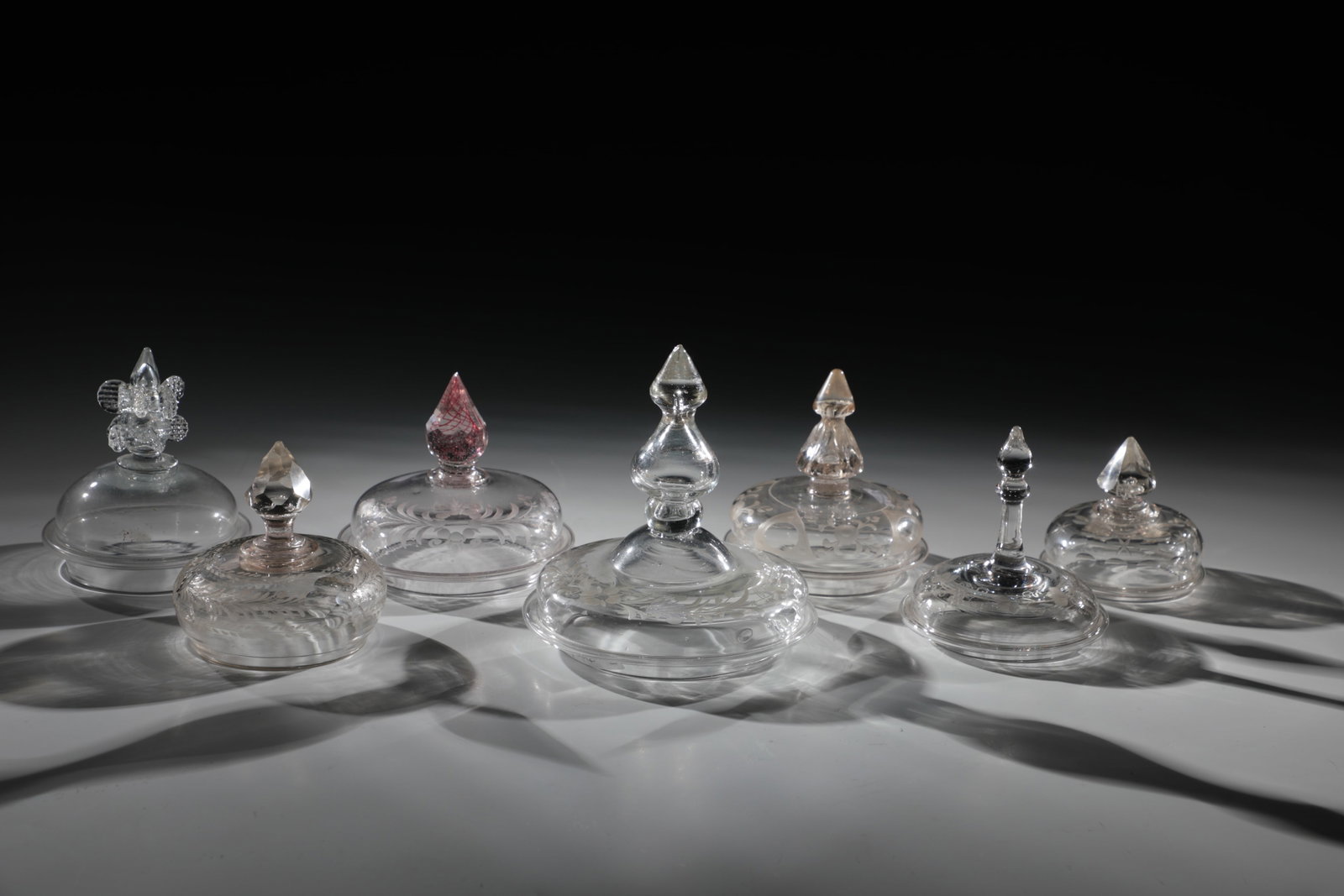 Mixed Lot of Seven Lids: Mixed lot of seven lids, 18th century, colourless glass, partly engraved. Differently shaped and sharpened or pinched knobs, partly chipped. D. 6 - 10 cm Konvolut sieben Deckel 18. Jh. Farbloses Glas