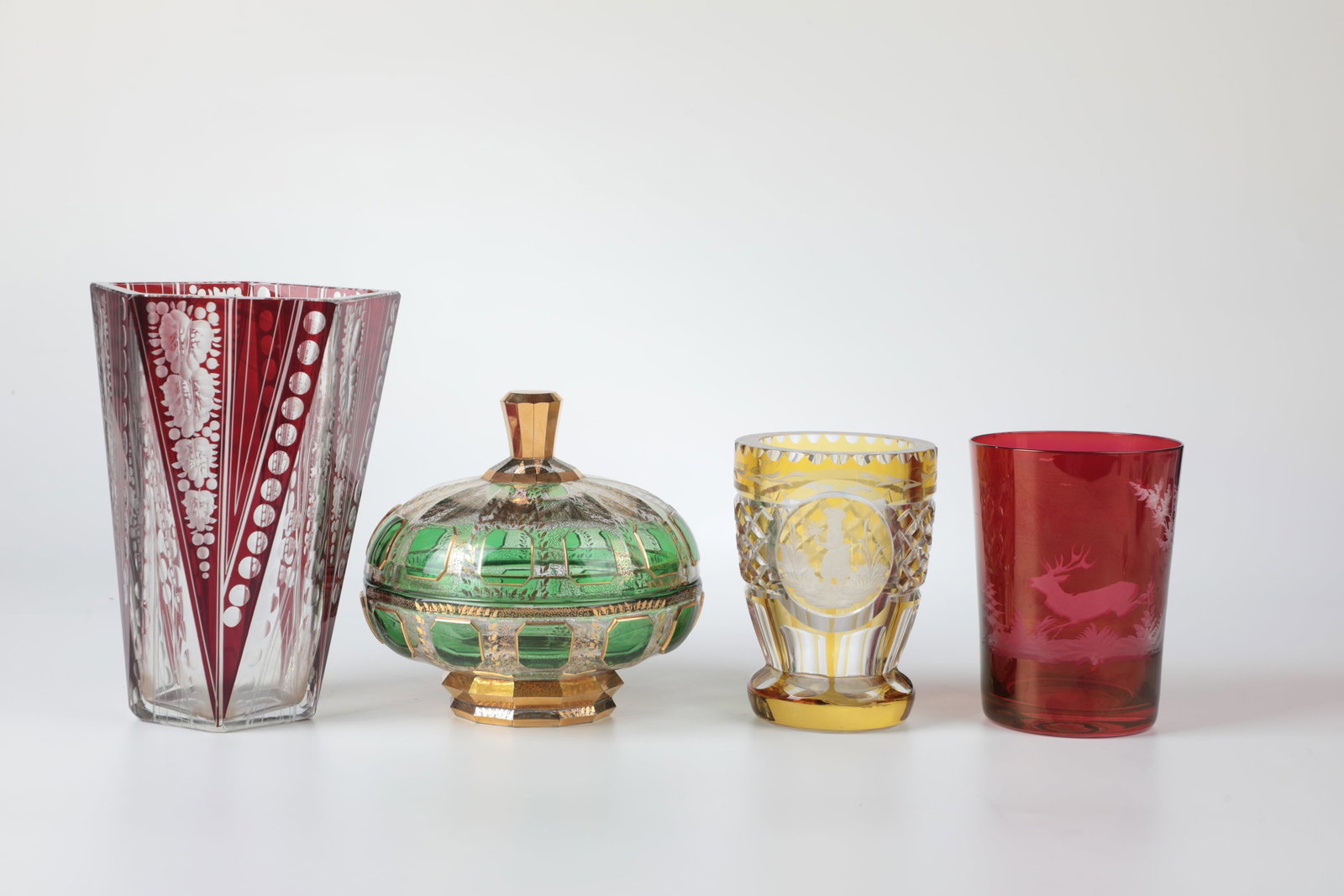 Mixed lot of four parts glass: Mixed lot of four parts of glass Bohemia, 20th century. Consisting of a red glazed cup with cut depictions of a deer. h. 13 cm, a yellow-stained one with a cut depiction of a lady with a flower H. 13