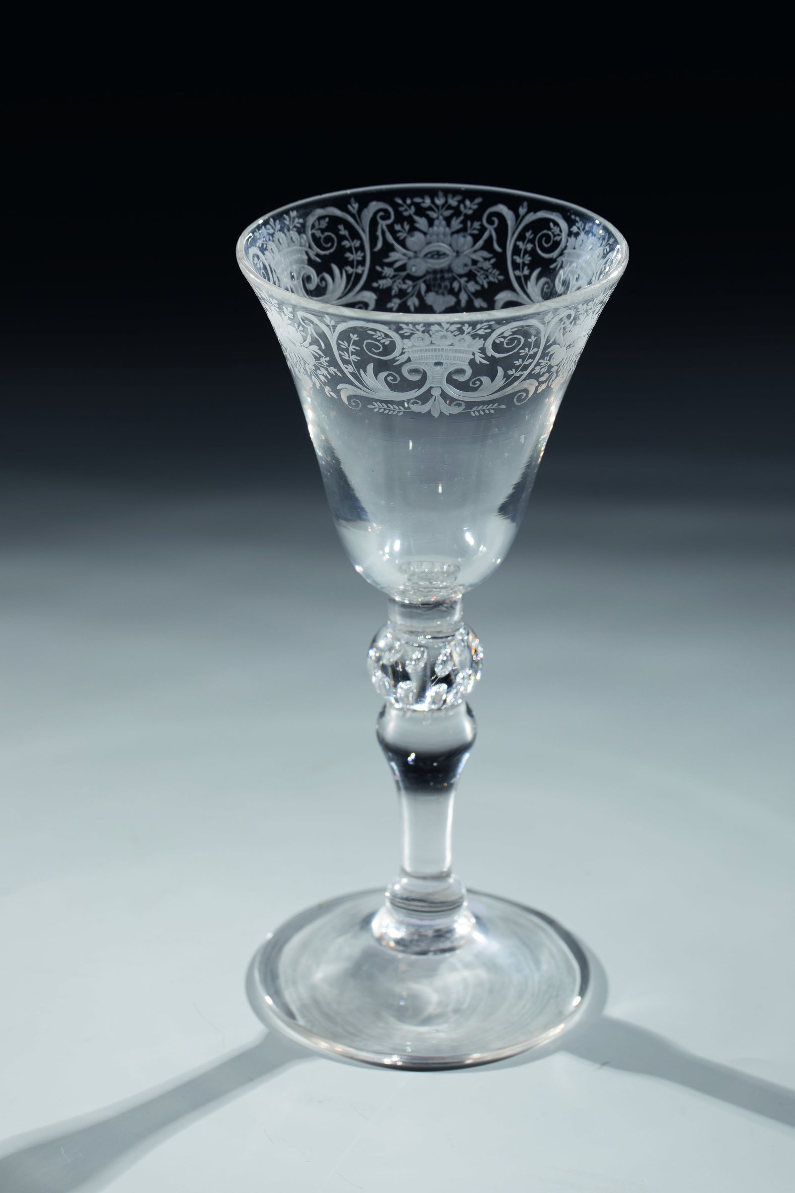 Cup: Goblet glass England, cut Netherlands, c. 1760 Raised disc base with tear-off, slender baluster shaft. Double nodus with pierced air bubbles. Finely cut, floral curtain border on the widened cuppa.