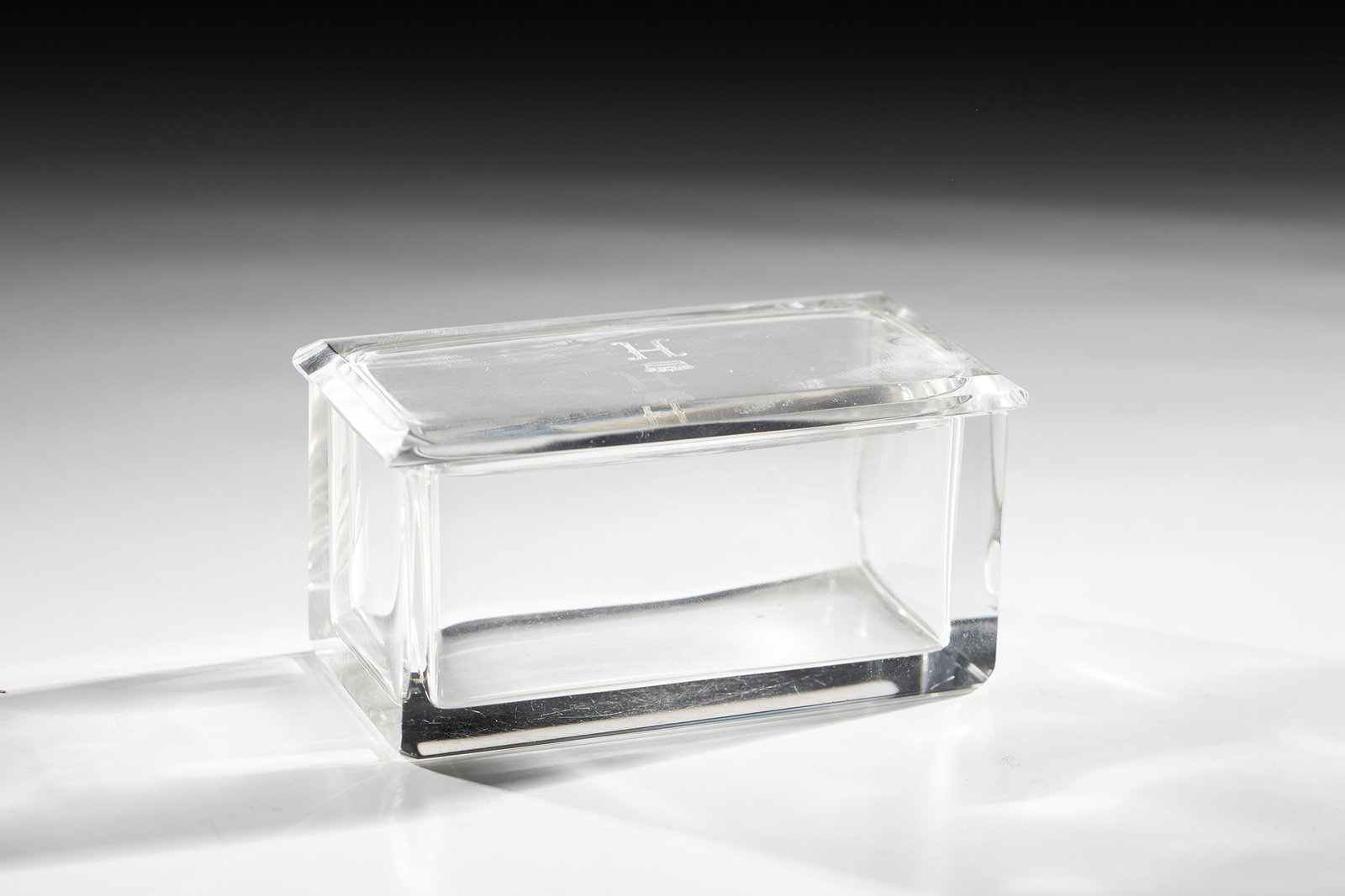 Lidded jar: Lidded box early 20th century Colorless glass. Rectangular body with polished corners. The plug-in lid is engraved with a crowned ''H''. H. 5 cm; L. 10 cm; D. 4.6 cm. Deckeldose Anfang 20.