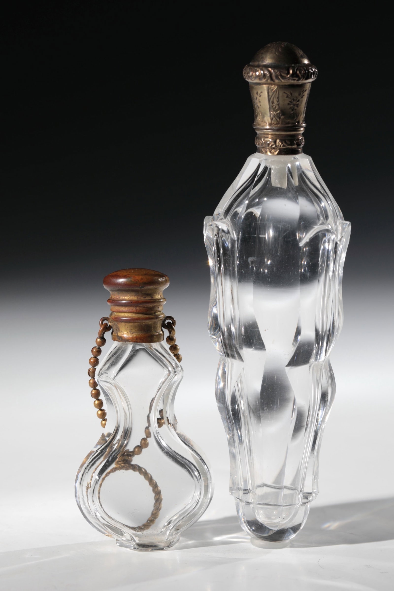 Two smelling vials: Two Smelling Vials France, 19th century Colourless glass. Flattened wall with peeled sides. Metal mounts. H. 7 or 13 cm Zwei Riechfläschchen Frankreich, 19. Jh. Farbloses Glas. Abgeflachte