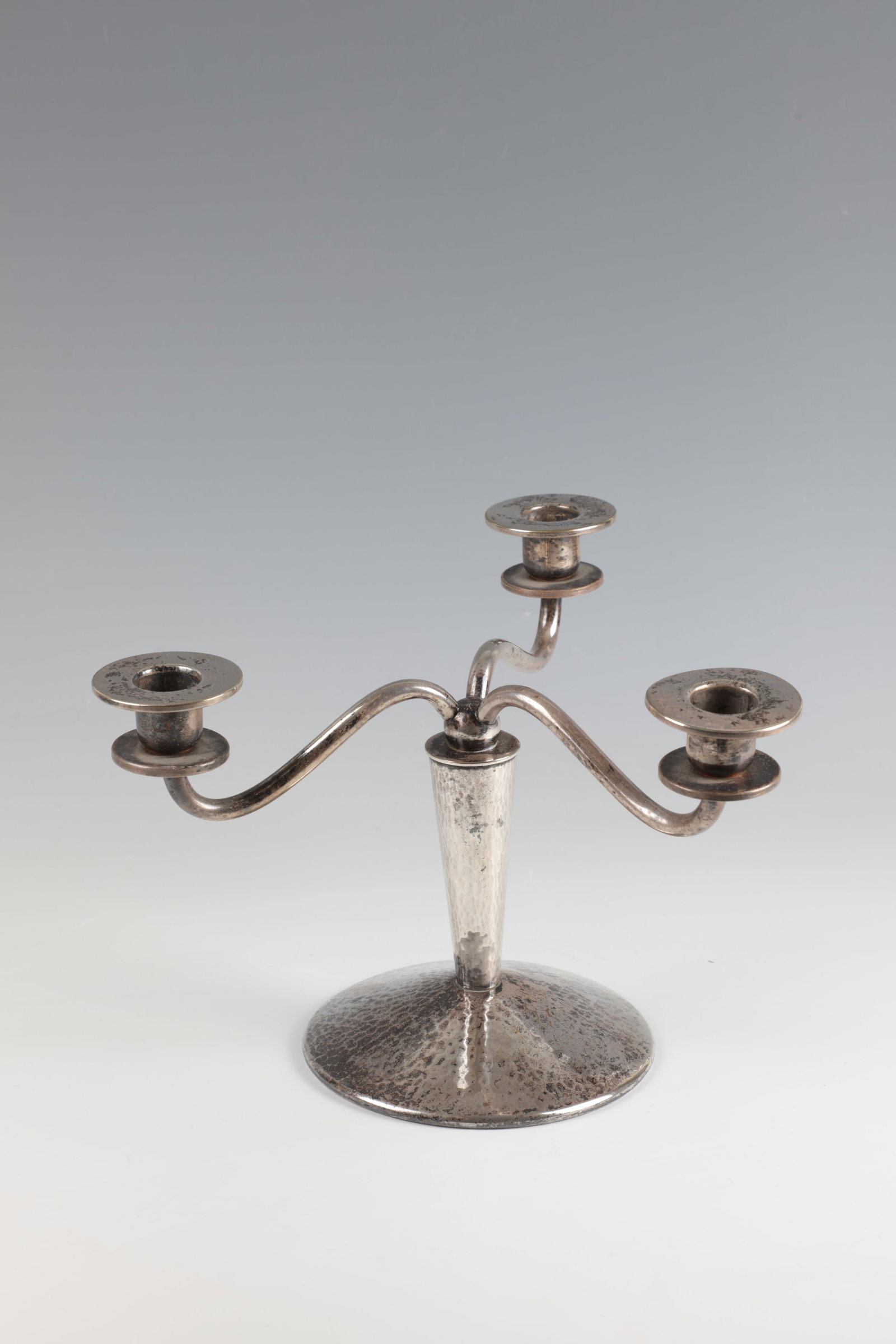 Three-armed candlestick: Three-armed candlestick WMF, Württembergische Metallwarenfabrik, Geislingen, around 1925 Silver-plated metal. On a round, slightly curved base with a hammered surface. Curved, asymmetrically guid