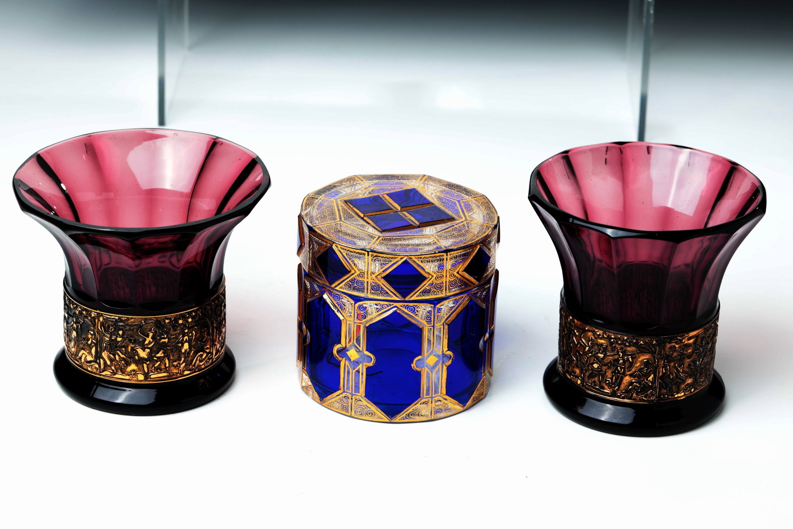 Pair of vases and lidded box: Pair of vases and lidded box August Walther & Söhne, Moritzdorf, near Ottendorf-Okrilla near Dresden, c. 1930 Amethyst-coloured pressed glass. Below the expansive, pseudo-faceted wall, there