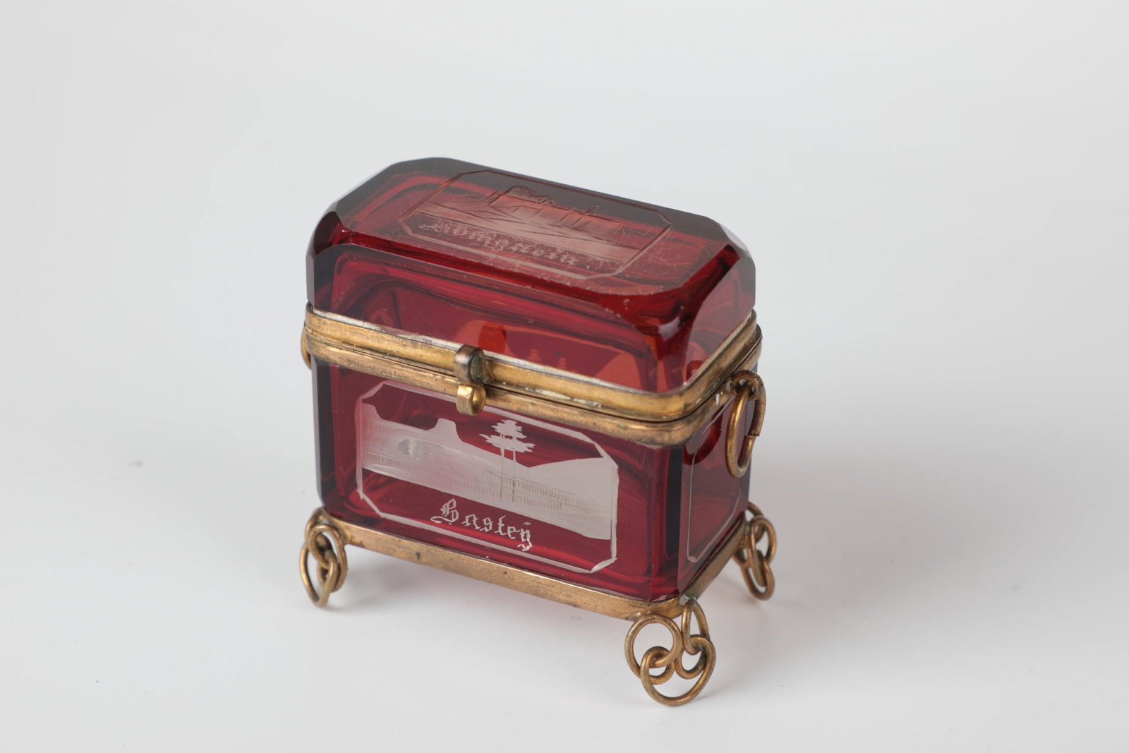 Small lidded box with views of Saxon Switzerland: Small lidded box with views of Saxon Switzerland Bohemia, M. 19th century Colourless, red-glazed glass with vedute inscribed: ''Königstein or Bastey''. Brass mount. 6.5 x 3.5 x 7 cm Kleine