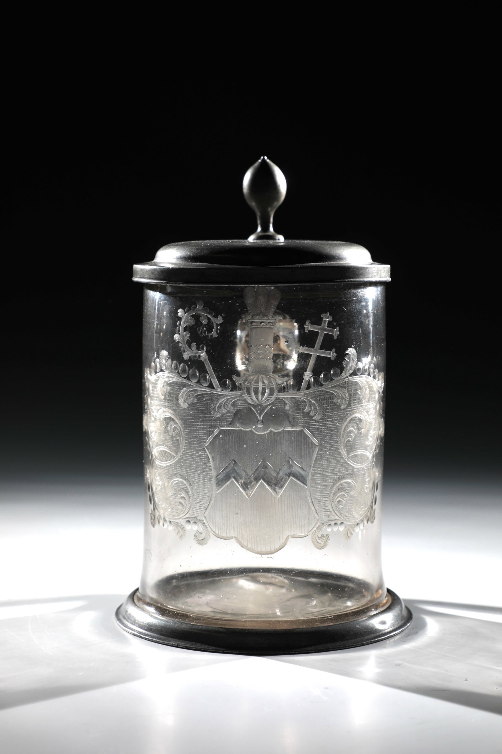 Mug with tin lid and coat of arms of a clerical dignitary: Jug with tin lid and coat of arms of a clerical dignitary Bohemia, A. 18th century Colourless, slightly yellowish glass with tear. Frontal on the cylindrical wall in partly bleached matt cut coat of