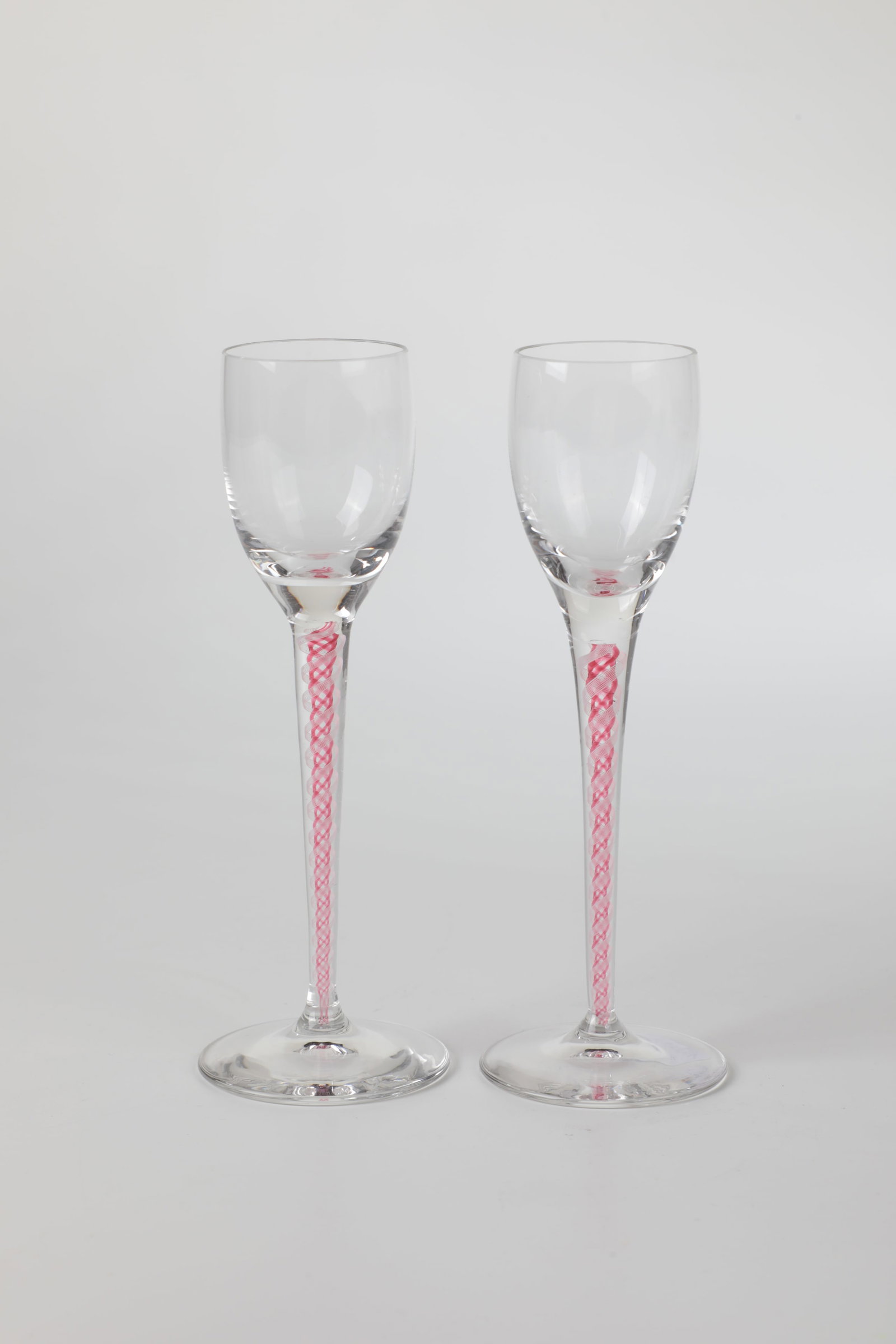 Pair of liqueur glasses: Pair of liqueur glasses Bohemia, around 1900 Colourless glass. Long, delicate, slightly conical shaft with enclosed filigree frosted glass and pink threads in a spiral pattern. H. 15 cm each. Paar