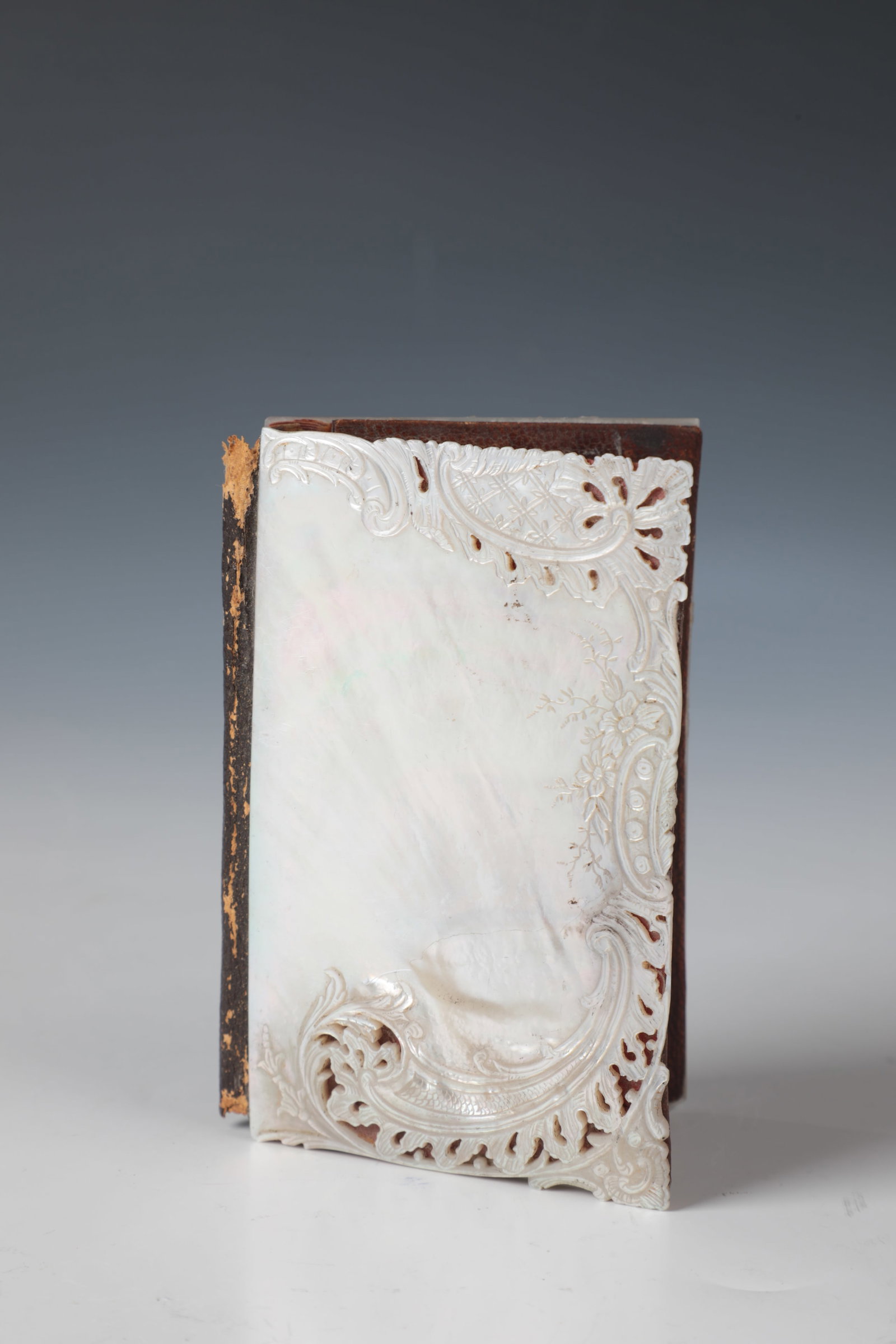 Business card holder: 19th century business card holder Top and bottom made of mother-of-pearl and held together with leather. Top with carved, partially openwork decoration: rocailles, cartouches and flowers. Min.