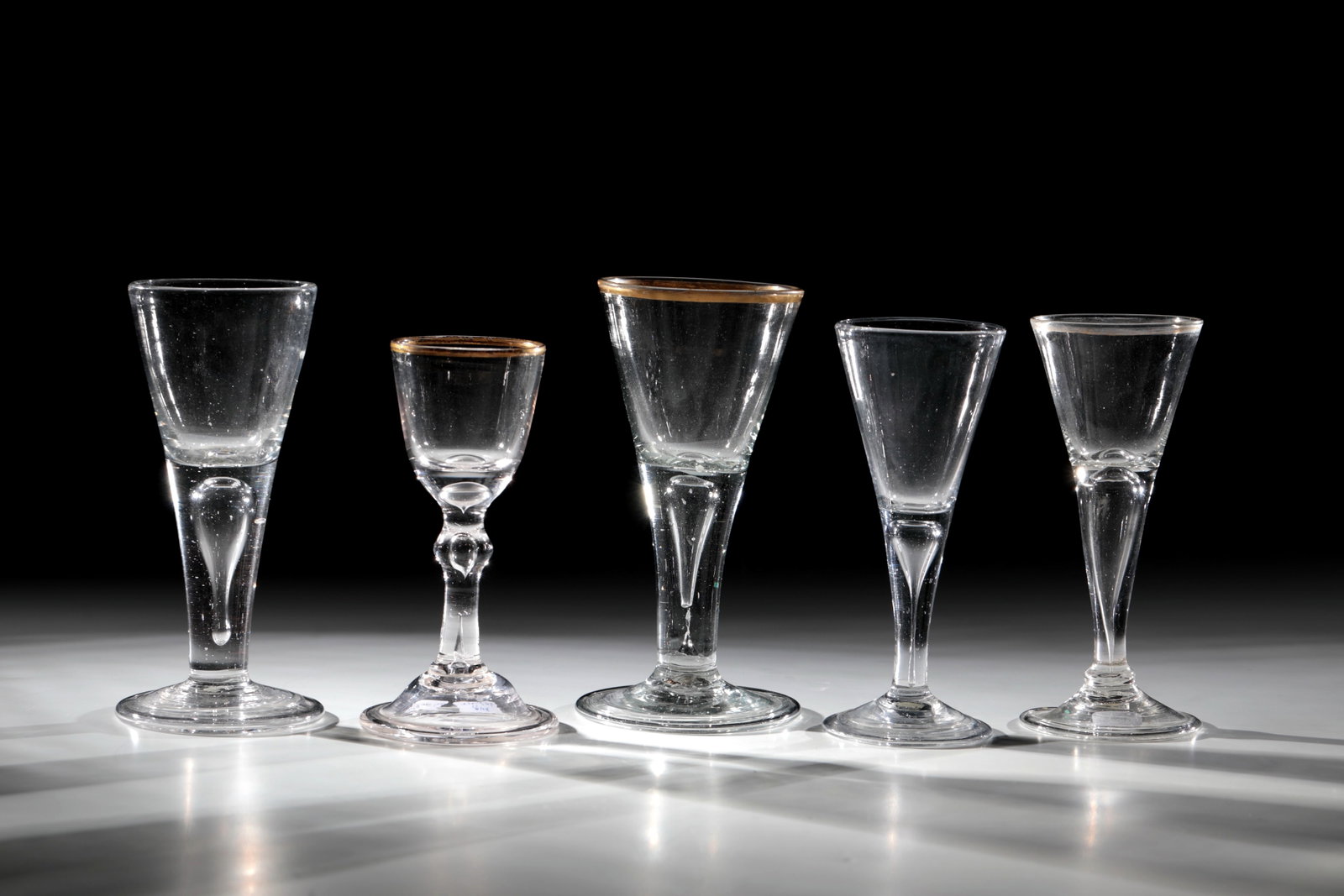 Mixed Lot of Five Chalices: Mixed lot of five chalices, Germany, 18th century, colourless glass with tear-off. Disc feet with folded edge downwards. Two with hollow shaft. Three chalices with gilded, partly rubbed copper land.