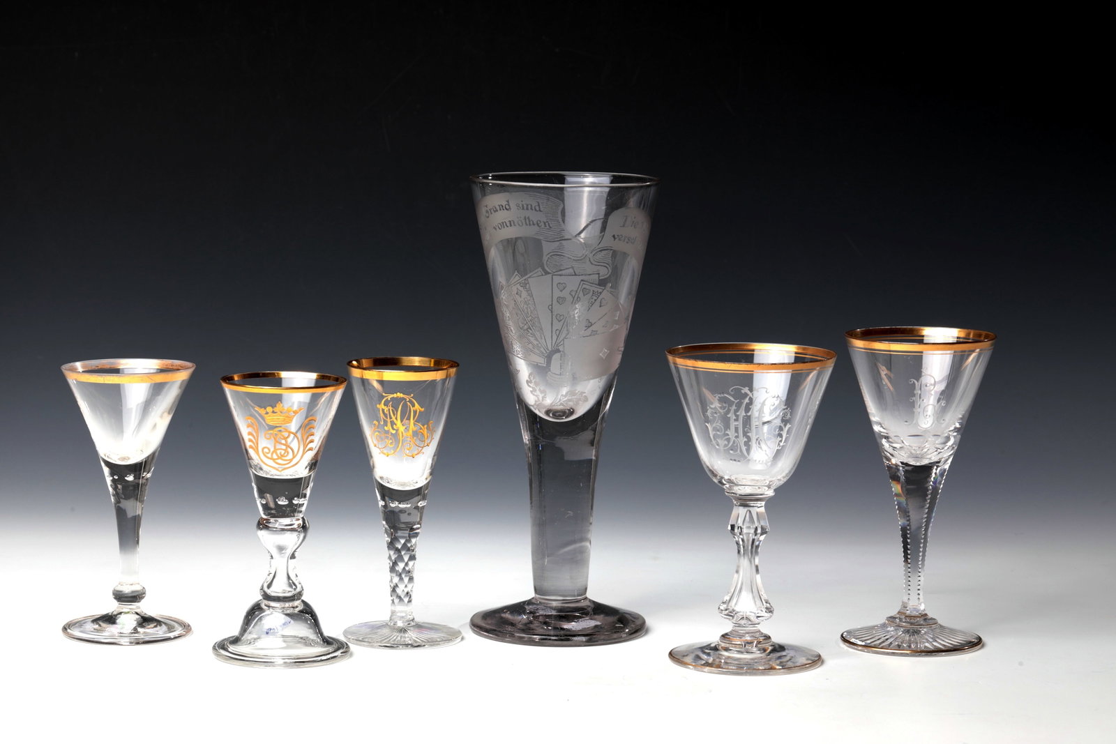 Mixed Lot of Five Chalices: Mixed lot of five chalices Josephinenhütte, 2H. 19th century Colourless glass with partly gilded initials or with an etched representation of a grand in skat with the corresponding motto: "At the