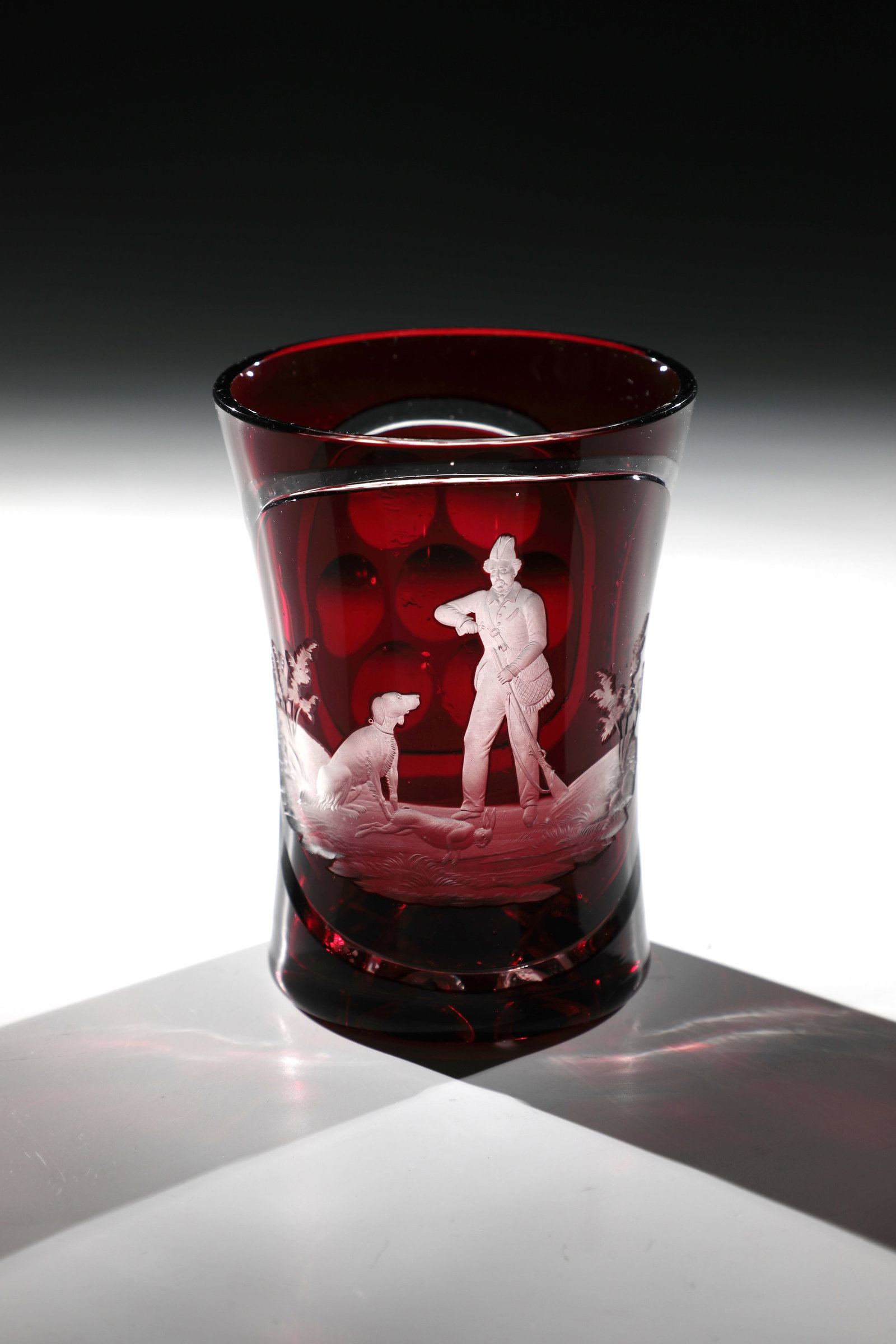 Hunting Mug: Hunting cup Bohemia, 2nd half of the 19th century Colourless, ruby-red overlaid glass. Frontal on the waisted wall in a very fine deep cut depicting a hunter filling his shotgun with gunpowder, on