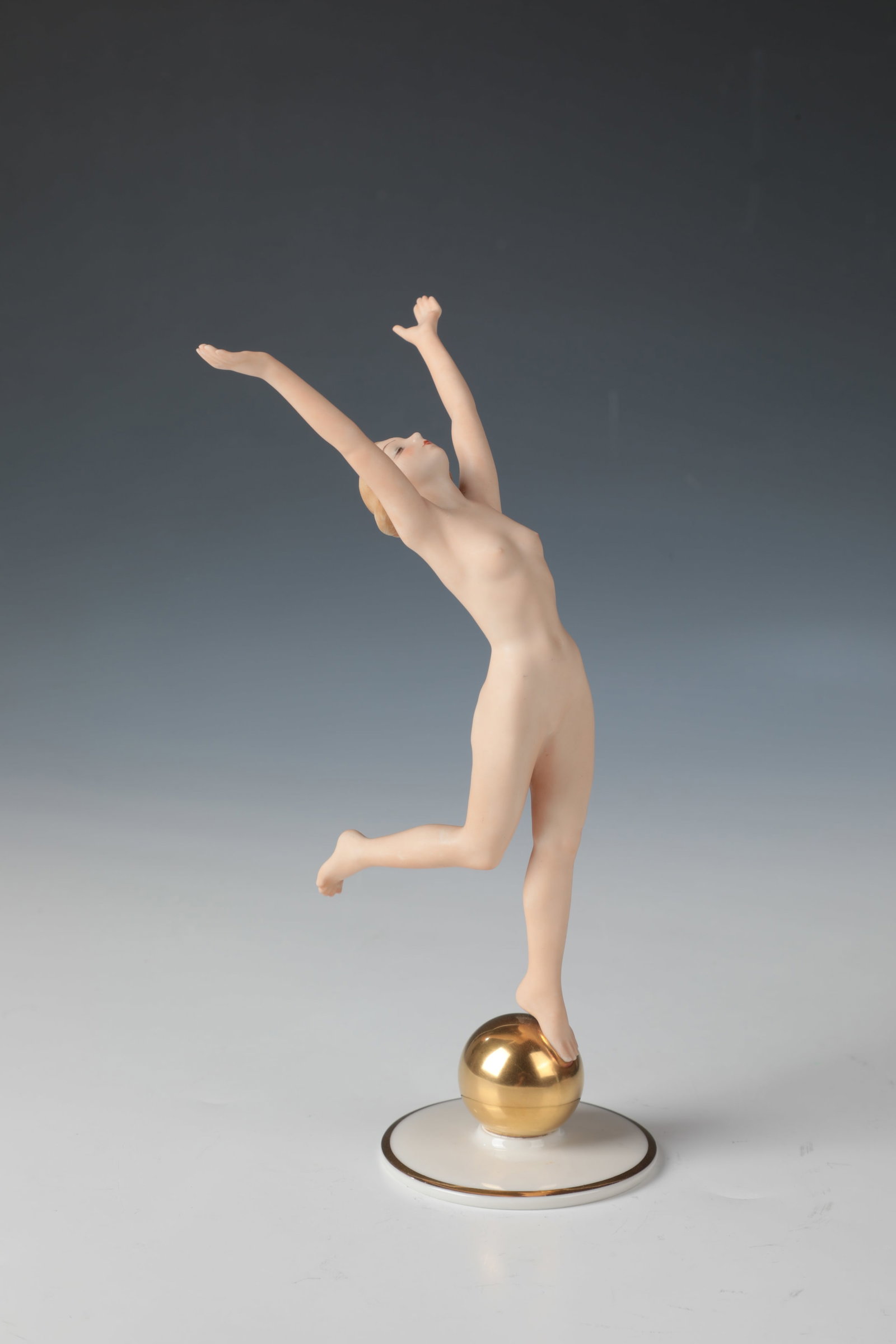 Sun Child: Sonnenkind Karl Tutter (design), Hutschenreuther AG, Selb, 1939 - 1964 On a round base with a gold ball in overglaze painting, a female nude in dancing motion. Inscribed in the bottom: Tutter,
