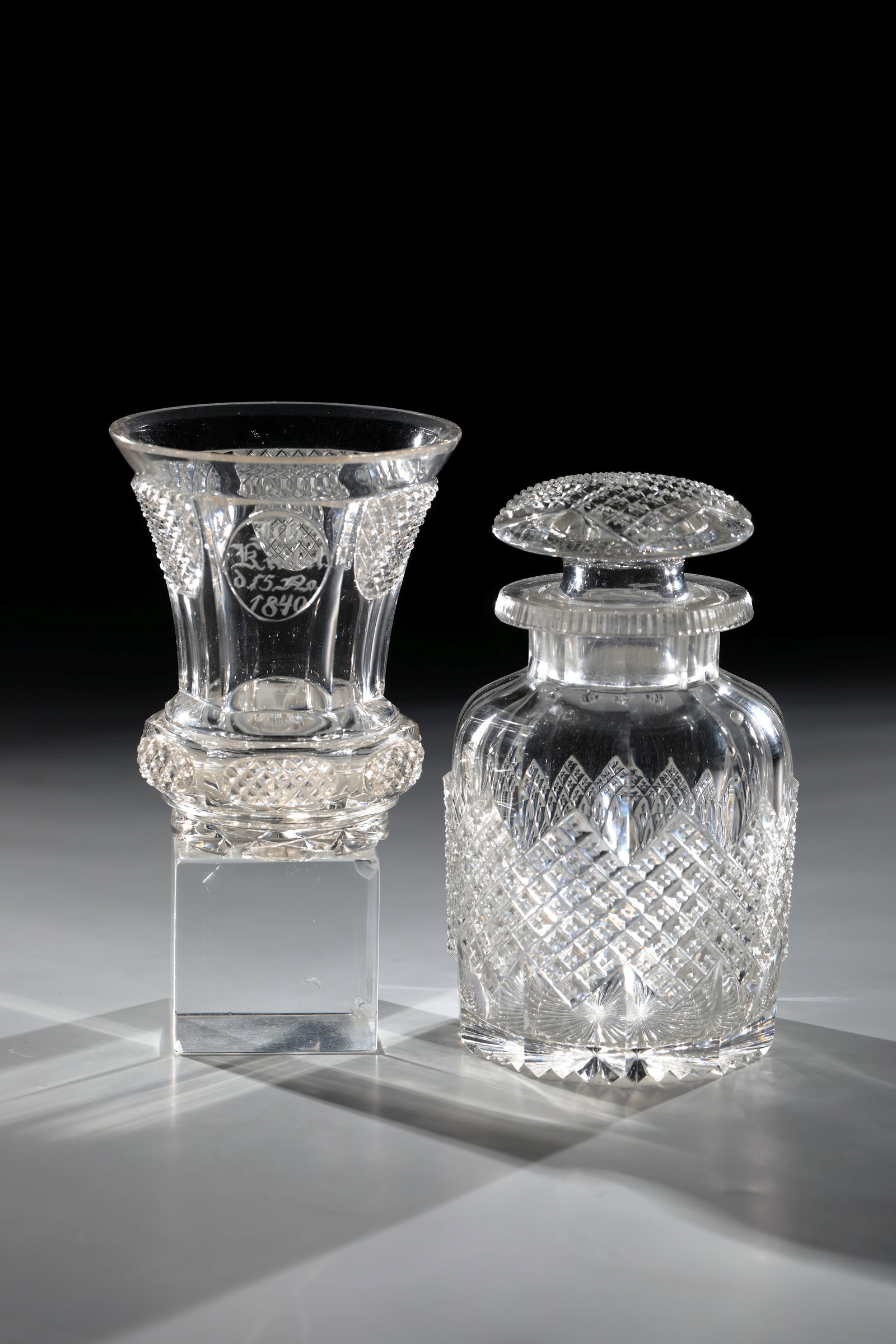 Bottle with mug: Bottle with Mug New World, dated 1840 Colourless glass with rich facet and stone cut. Beaker frontal with highly cut oval medallion and inscription: ''I.G. Knebel. 15. No. 1840''. H. 14 or 10.5 cm Fla