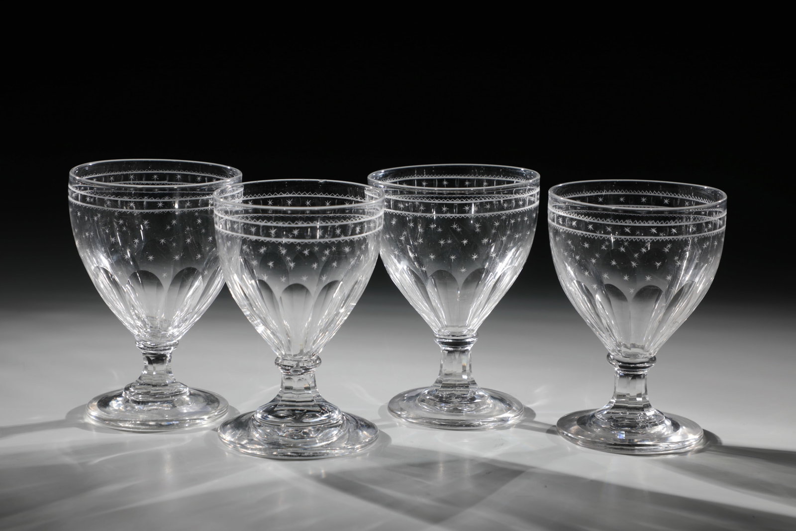 Four Empire Goblets: Four Empire Goblets England circa 1820 Colorless glass. Disc base with ground tear-off. Shaft and tip base peeled. Below the edge of the muzzle circumferential border made of olive cut and star