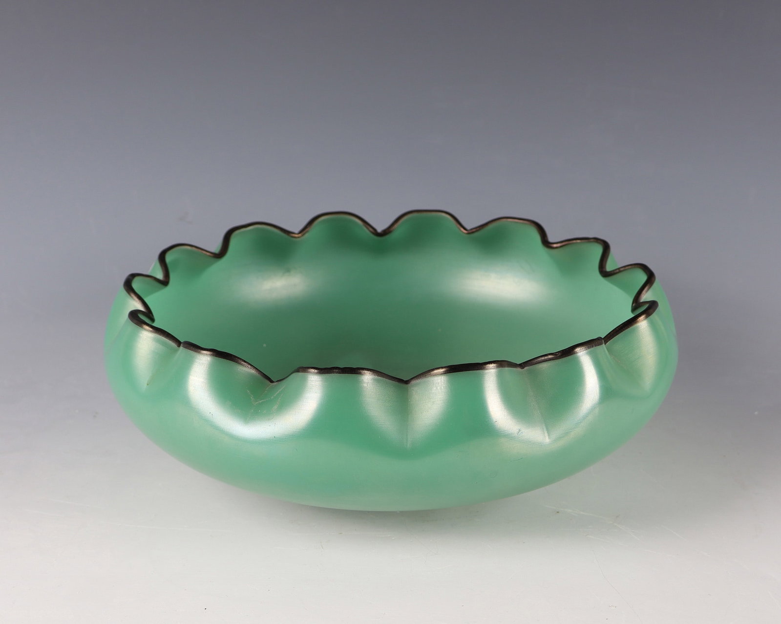 Shell: Bowl Bohemia, c. 1930 Colourless glass, green underlay. The wavy muzzle edge with black-violet thread overlay. Iridescent. H. 9.5 cm; D. 24.5 cm. Schale Böhmen, um 1930 Farbloses Glas, grün