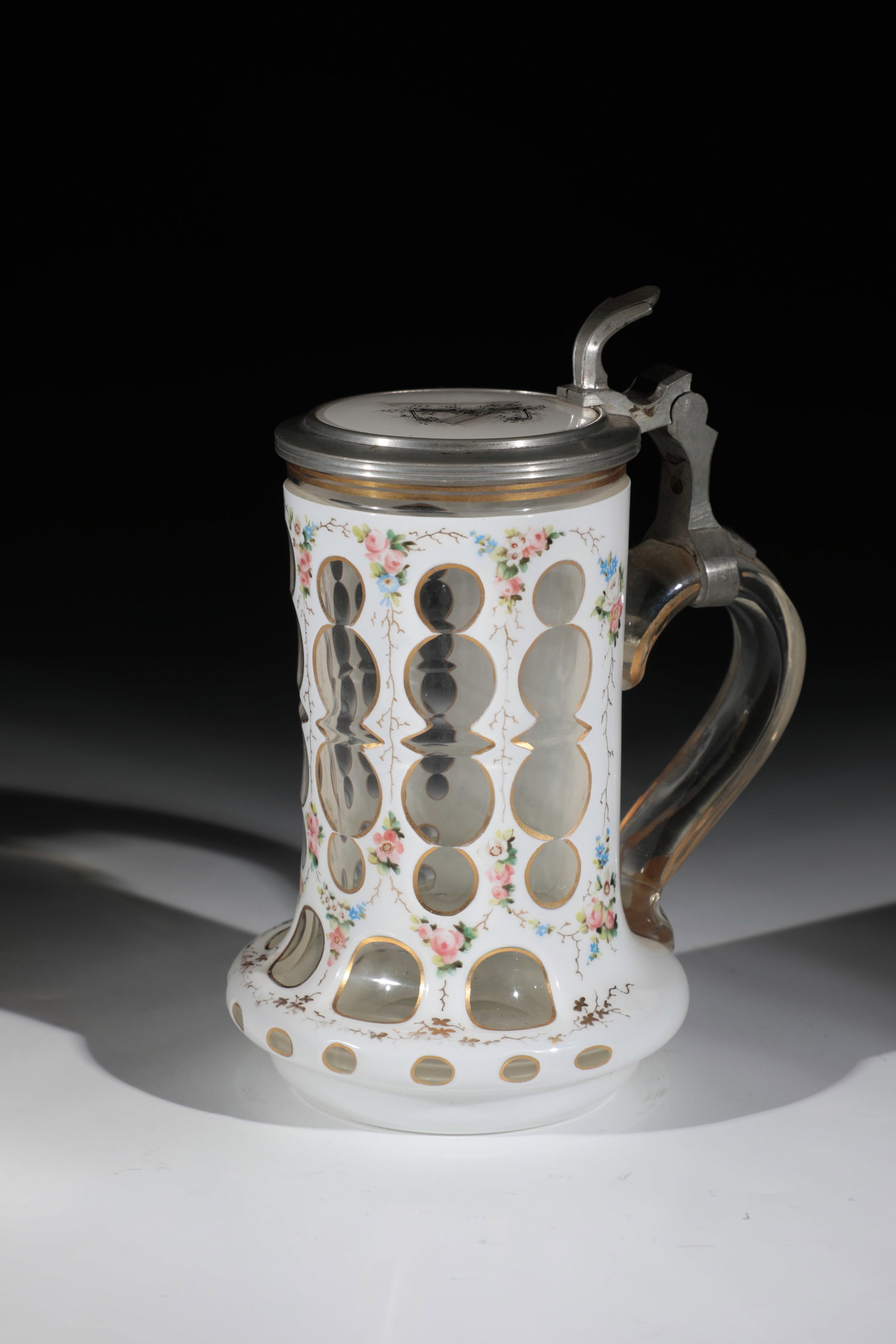 Lidded jug with tin enamel overlay: Lidded jug with tin enamel overlay Bohemia, 19th century Colourless glass with ornamentally cut tin enamel overlay and gilded edges. In between, flower garlands in very fine, polychrome enamel and