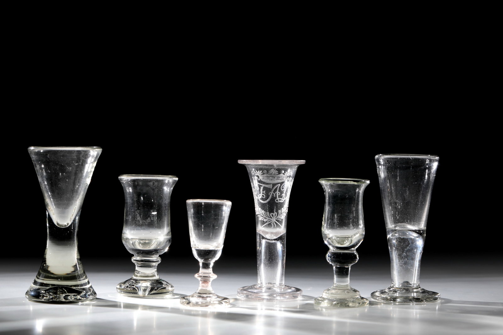 Mixed Lot of Five Shot Glasses: Mixed lot of five shot glasses North German 18th / 19th century Colourless glass with tear scars. The so-called coachman's bone with a massive stand, a shot glass with a hollow baluster and three