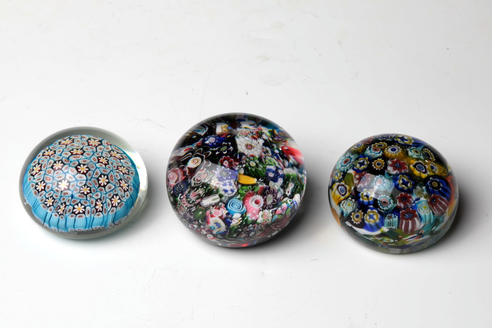 Three Paperweights: Three Paperweights Clichy, mid-19th century and Murano 20th century. So-called End of the Day. Colourless upholstery with various millefiori rods set all over the area. Surface with signs of wear