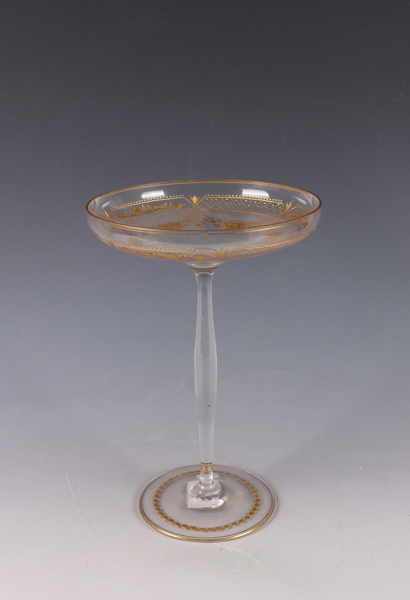 Tazza: Tazza Wohl Vienna, c. 1900 Colourless glass. Flat, bowl-shaped cuppa with circumferential, engraved border of stylised leaf and flower motifs in polished gold. Foot also with engraved border in