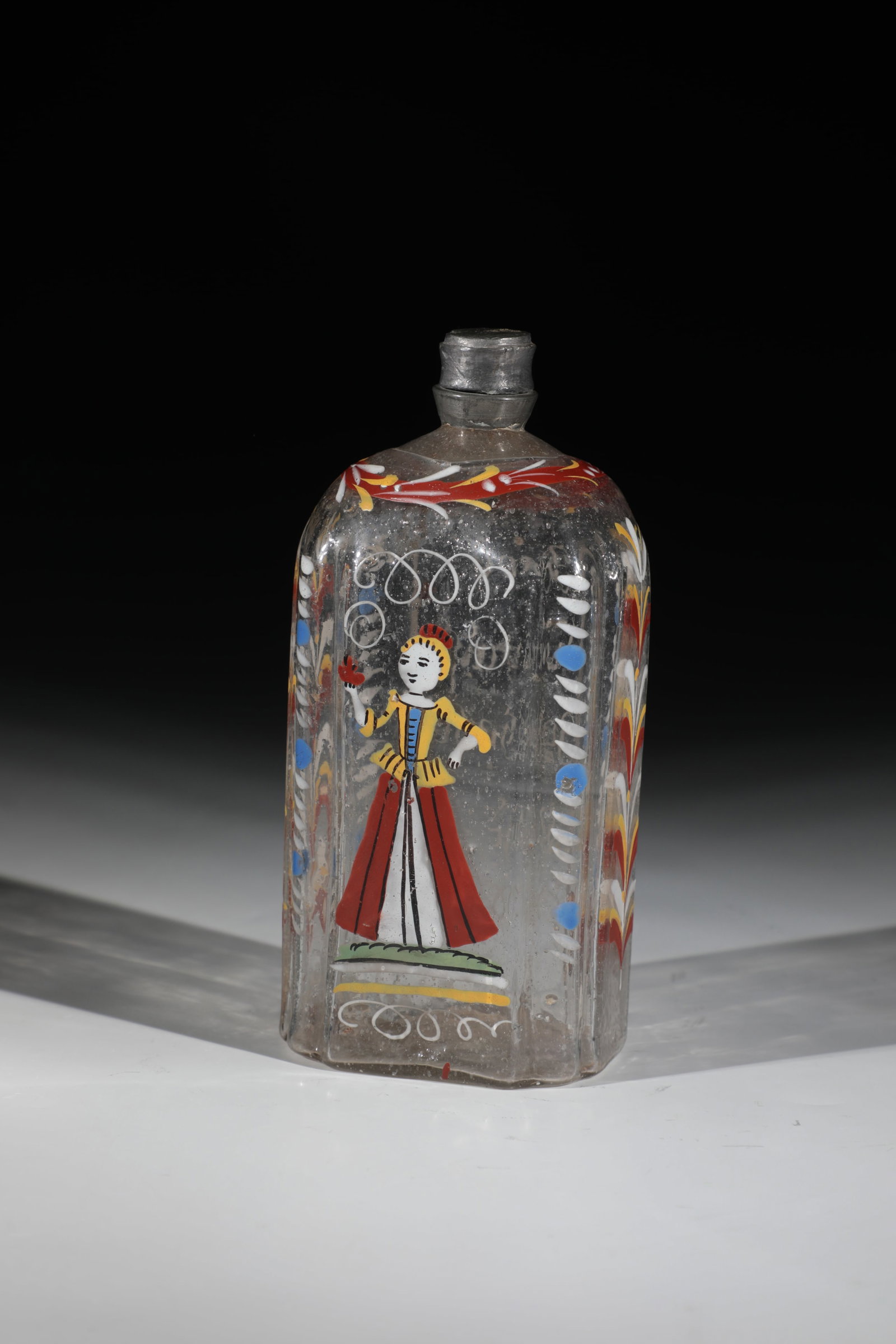 Liquor bottle with erotic saying: Schnapps bottle with erotic saying German, 18th century Colourless glass with tear-off. Rectangular wall in cross-section with round edges. Frontal in polychrome enamel painting a lady. Laterally