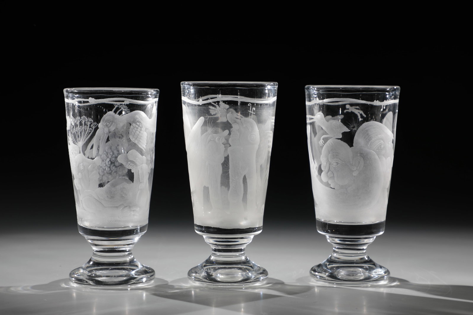 Three foot cups: Three foot cups Christian Schmidt for Glashütte Valentin Eisch, 1993-95 Colourless glass. Circumferential fantasy engraving décor. Inscribed in vibro-engraving on the stand: ''ChriSch 93''
