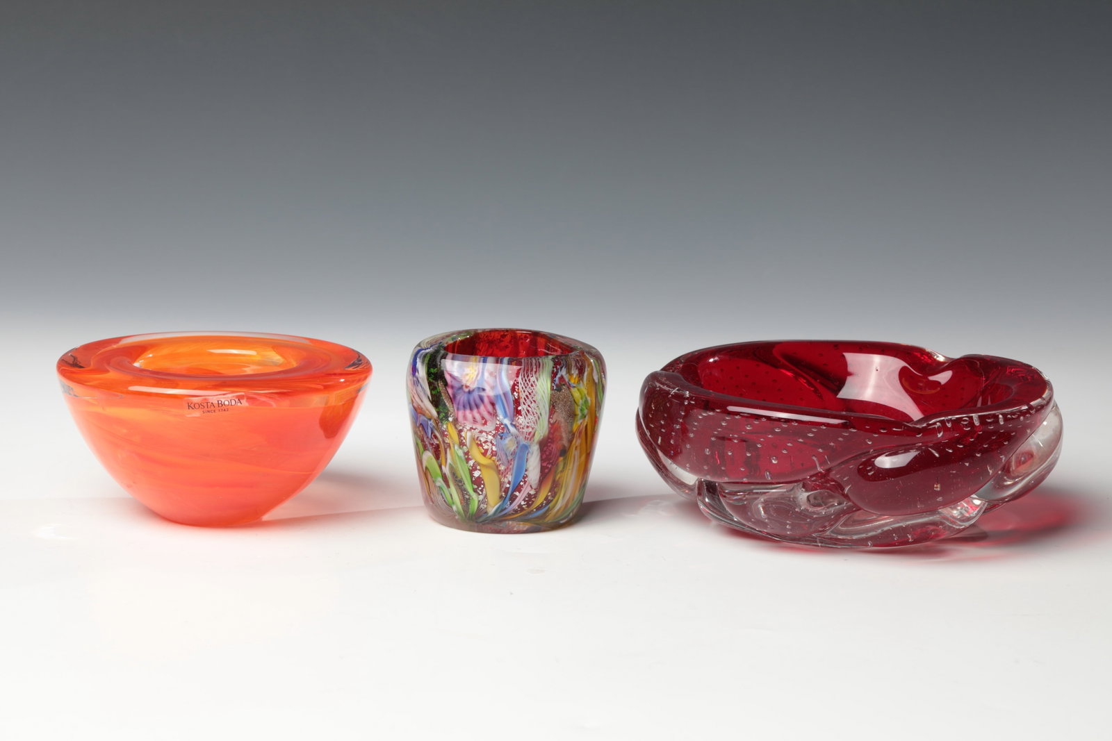 Two bowls and a vase: Two bowls and a vase Kosta Boda, and Murano, 20th century Thick-walled, colourless glass with orange interlayer decoration. Bottom inscribed: Kosta Boda (etching stamp). Original stickers of the