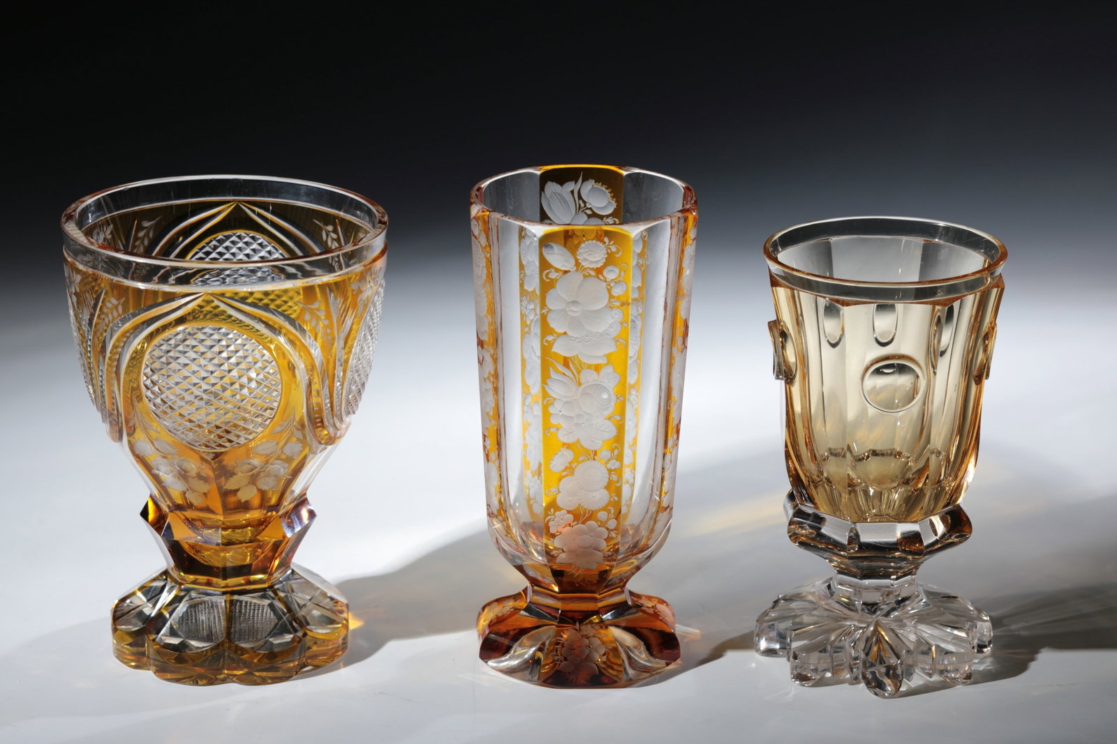 Mixed lot of three foot cups: Mixed lot of three foot cups Bohemia, 19th century Colourless, partly yellow-stained glass with rich cut decoration. H. 14 - 15.5 cm Konvolut drei Fußbecher Böhmen, 19. Jh. Farbloses, teils 