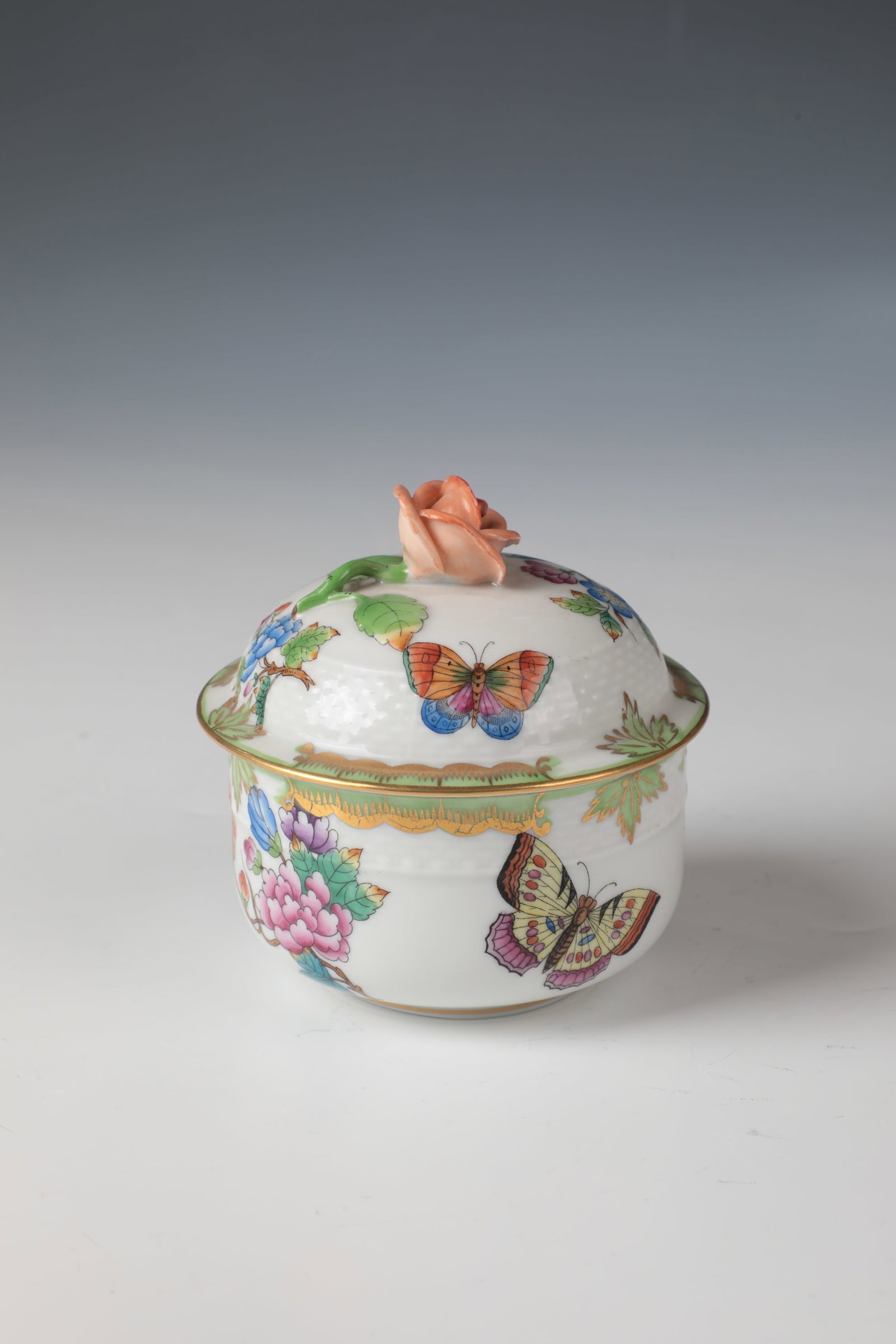 Sugar bowl: Sugar bowl Herend, 20th century porcelain. Round box with relief wicker decoration. Polychrome décor of butterflies and flower branches, complemented by a circumferential, green-heightened and