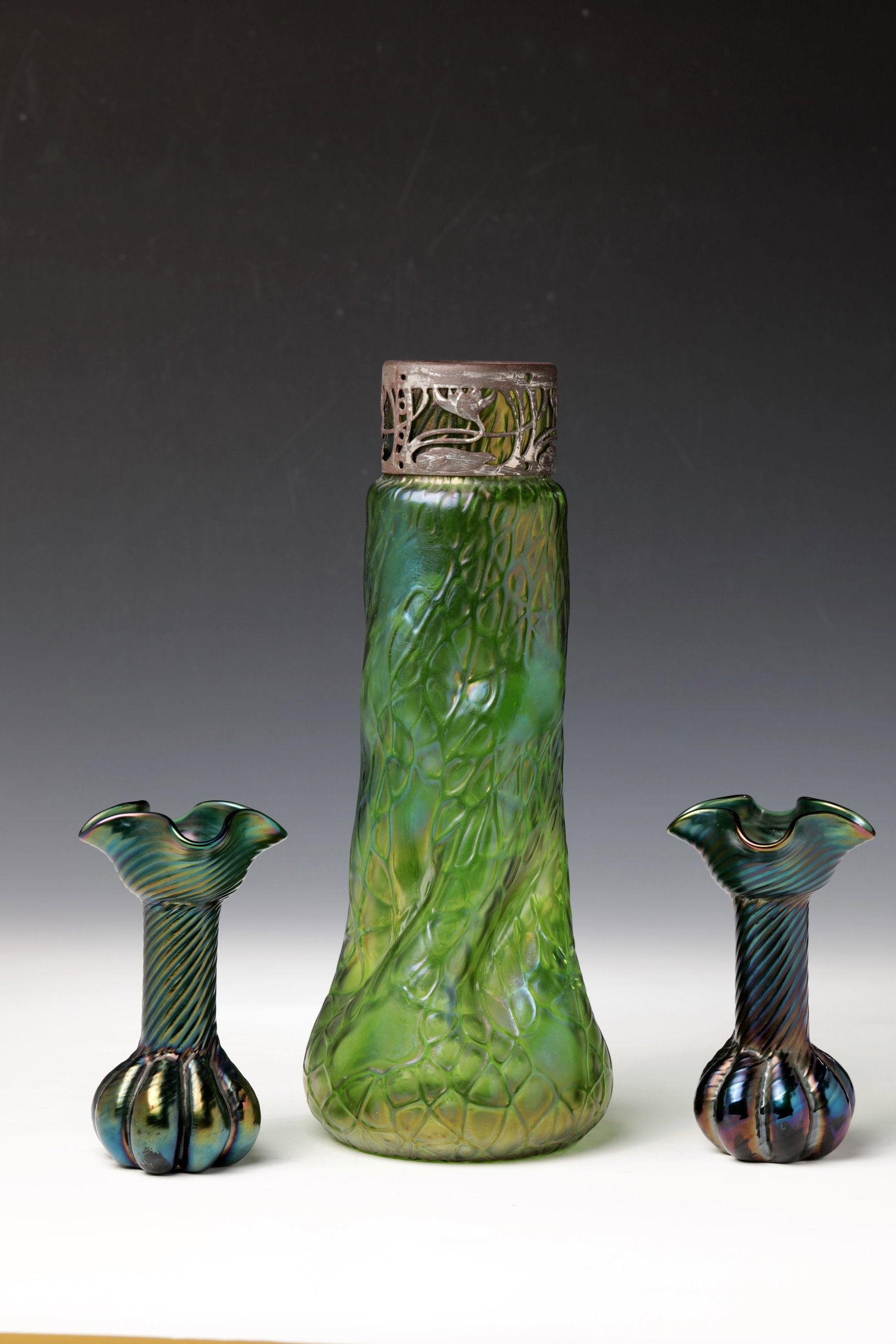 Mixed lot of three vases: Mixed lot of three vases Wilhelm Kralik Sohn, Eleonorenhain, after 1900 Dark blue-green, diagonally ribbed glass. Quatrefoil wavy muzzle. Iridescent. H. 13 cm. Or green glass, irregularly wound with g