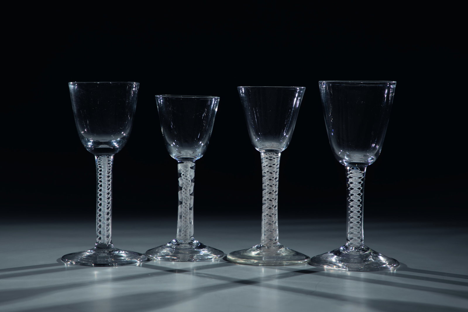 Mixed Lot of Four Thread Jars: Mixed lot of four thread glasses England, 18th century Colourless, partly grey-tinted glass with tear-off. Spirally enclosed frosted glass threads in the shaft. Egg-shaped cuppa. Partially ground