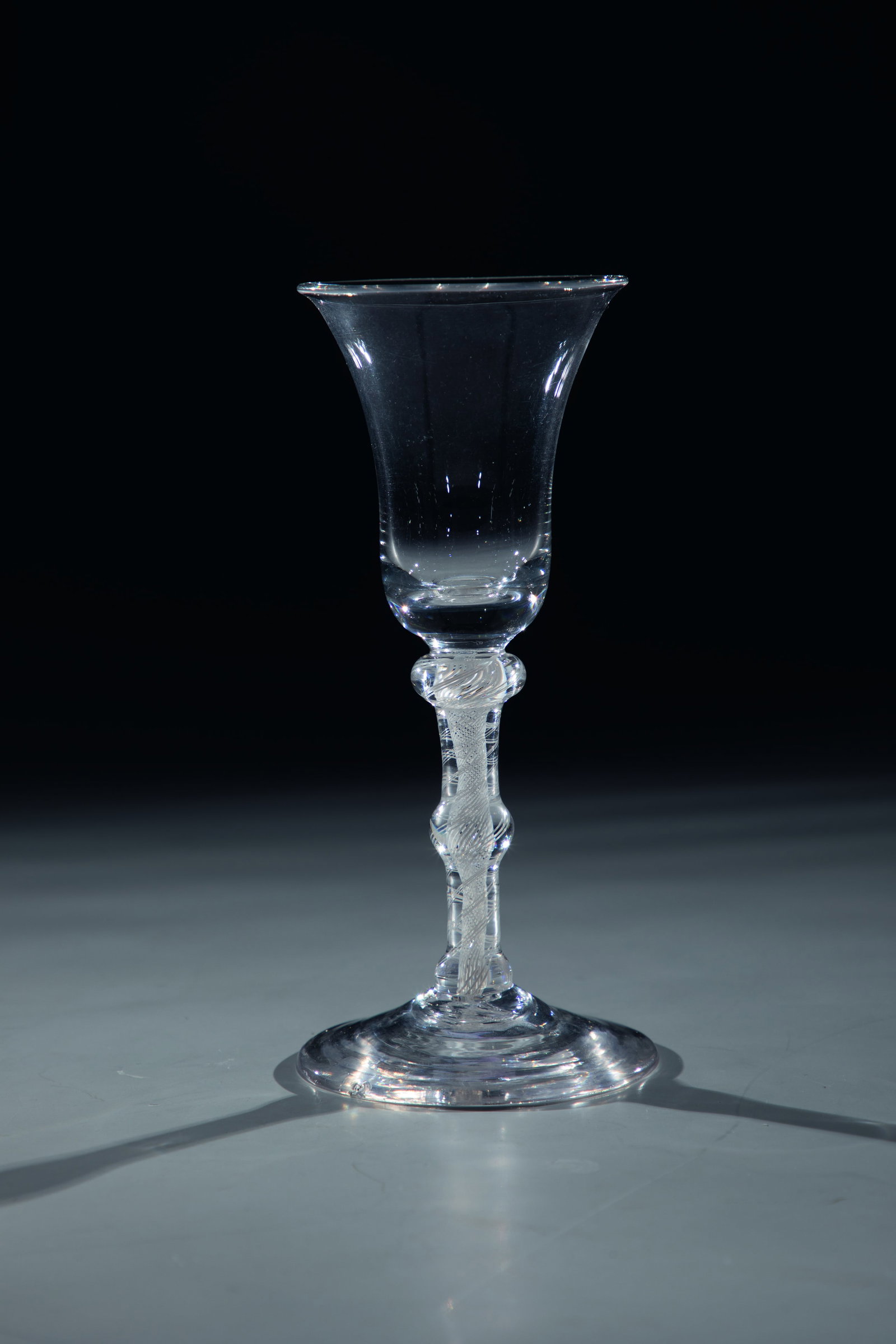 Filament glass: Thread glass England, 18th century Colourless glass with tear-off. Spirally enclosed frosted glass threads in the shaft with two nodes. Bell-shaped cuppa. foot bumped. H. 16.5 cm Fadenglas England,