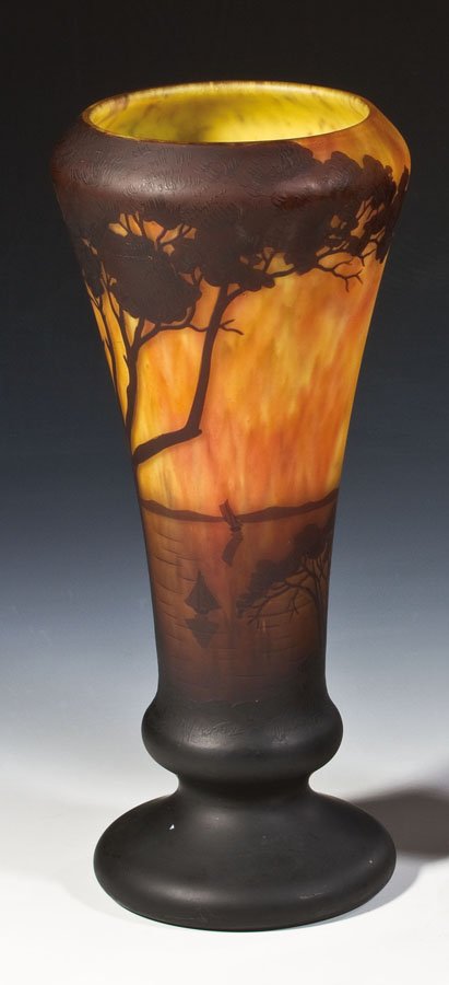 Fußvase mit südländischer Landschaft: Fußvase mit südländischer Landschaft Daum Frères, Nancy, um 1911 Farbloses Glas mit ein- und aufgeschmolzenem Pulver in Gelb, Rot und Violett. Auf der Wandung umlaufend reliefiert geätzter Dekor: