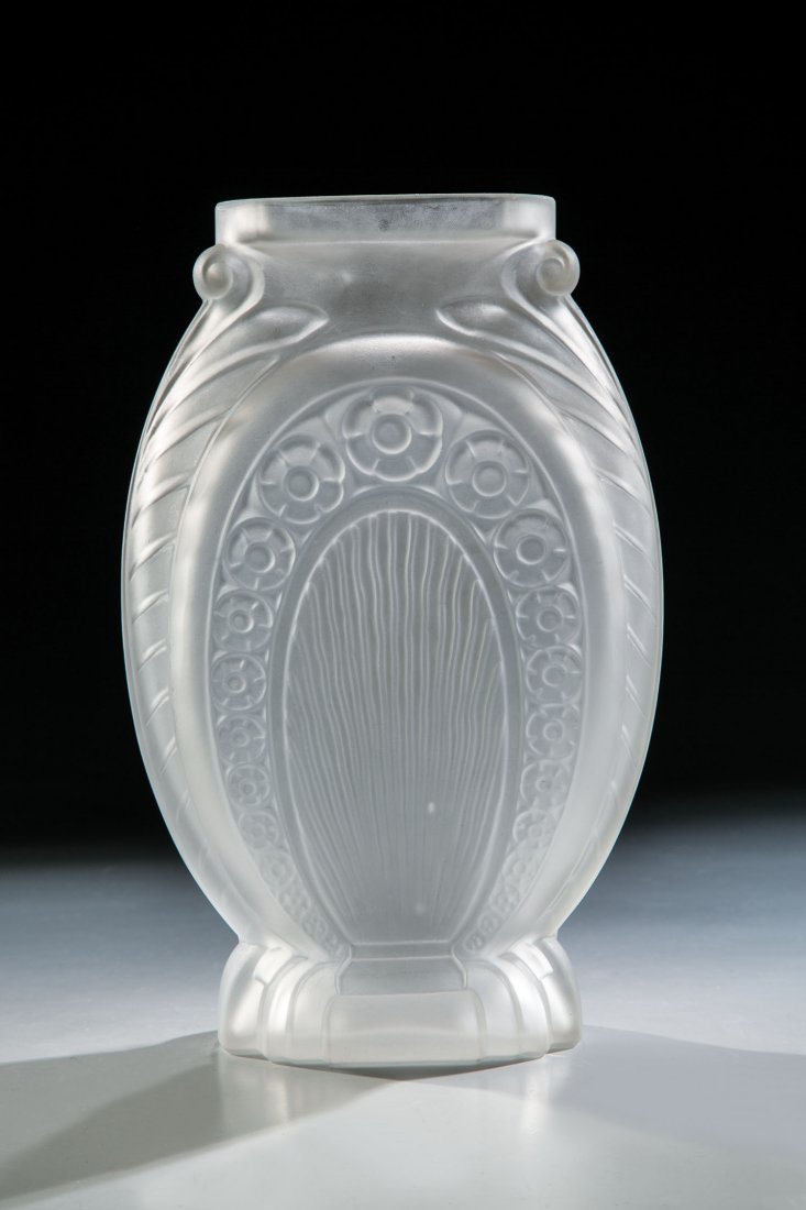 Vase: Vase Muller Frères, Lunéville, um 1925 Farbloses Glas, in die Form gepresst. Kräftig reliefierter Dekor: stilisierter Blütenfries, Wellendekor sowie in Voluten mündende Blätter. Boden bez.: MULL