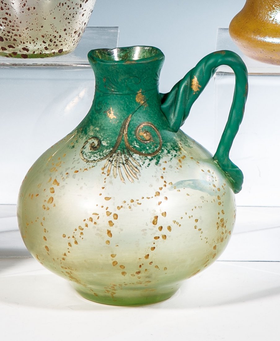 Zierhenkelvase ''Cephalonia mit Patinadekor'': Zierhenkelvase ''Cephalonia mit Patinadekor'' Loetz Wwe., Klostermühle, um 1904 Farbloses Glas mit aufgewalzter oder aufgedampfter schlackenartiger Schicht, durch Aufblasen im Model feinteilig zerris