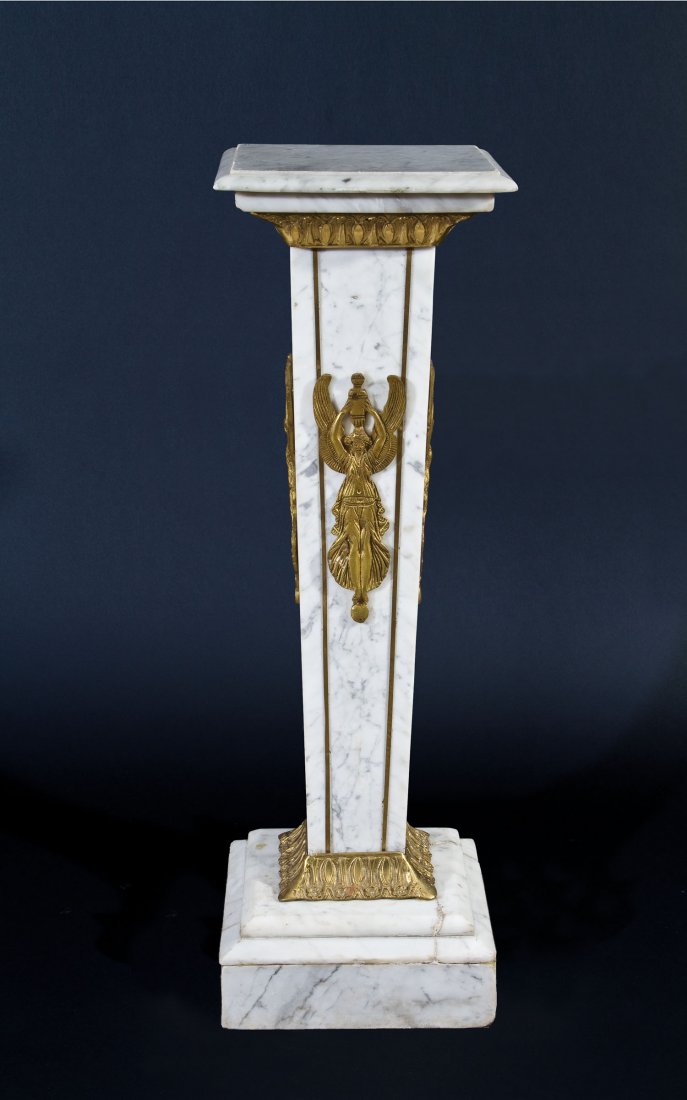 Marmorpodest: Marmorpodest Im Klassizistischen-Stil, Modern Nach unten verjüngter Schaft auf quadratischem Sockel. Basis und Kapitell mit Bronzeapplikationen. Allseitig Nikenmotive. Risse. 97 x 31,5 x 31,5.