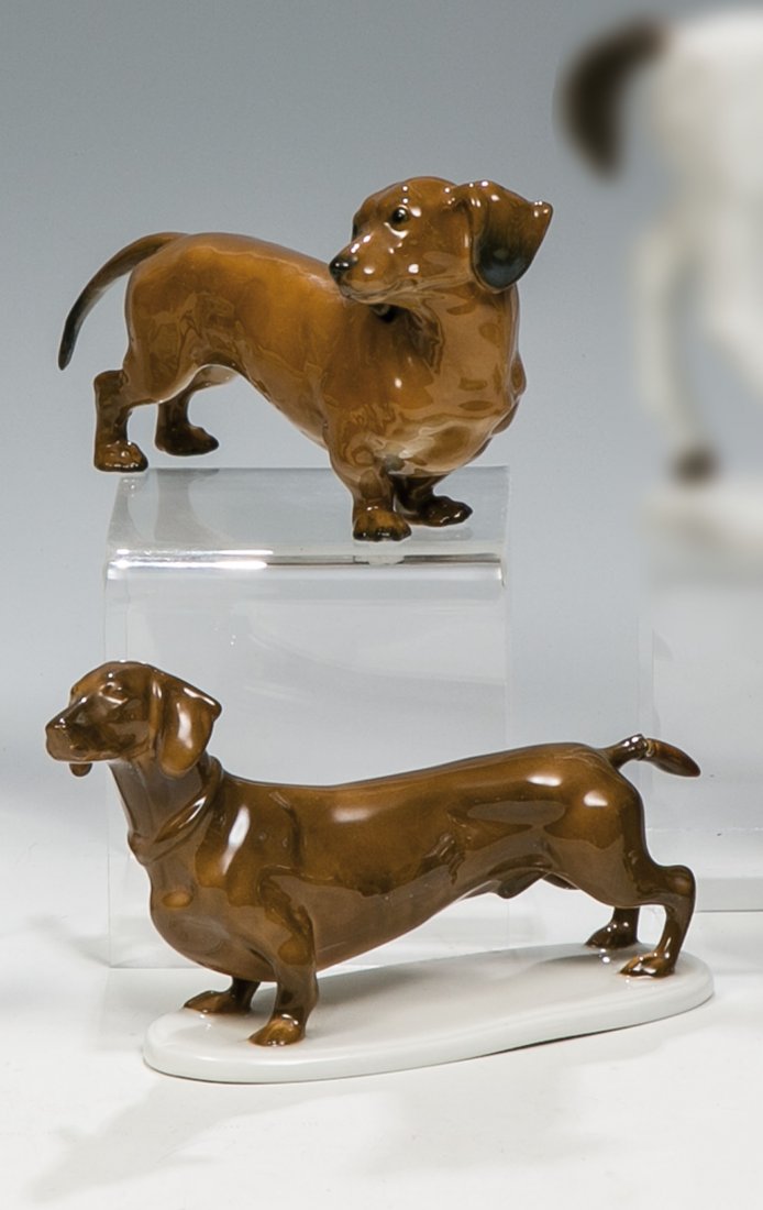 Zwei Dackel: Zwei Dackel E.v. Otto (Entwurf), Rosenthal, 1917 bzw. 50er Jahre Staffiert in naturalistischer Unterglasurbemalung. Ein Schwanz geklebt. Auf dem Sockel bez.: E.v. OTTO (in Unterglasurbraun aufgemalt).