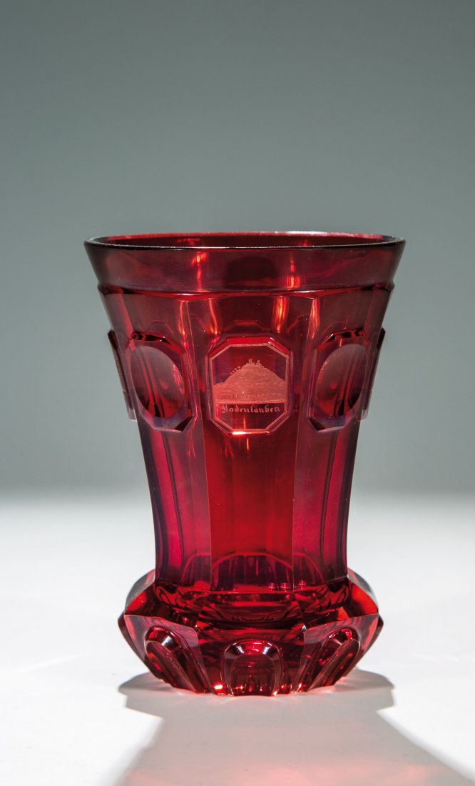 Becher mit Ansichten von Bad Kissingen: Becher mit Ansichten von Bad Kissingen Böhmen, um 1845 Farbloses, achtfach facettiertes, rot lasiertes Glas. Auskragender Stand mit hochgeschliffenen Knollen, Wandung mit hochgeschliffenen oktogonale