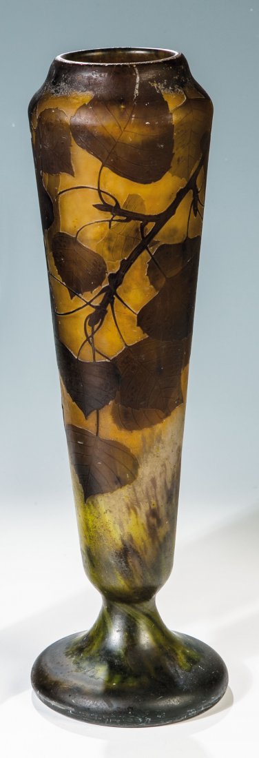 Fußvase mit Birkenzweigen: Fußvase mit Birkenzweigen Daum Frères, Nancy, um 1905 Farbloses Glas mit Pulvereinschmelzungen in Violett, Orange und Gelb sowie violettbraun überfangen. Umlaufend reliefiert geätzter Dekor: Blatt