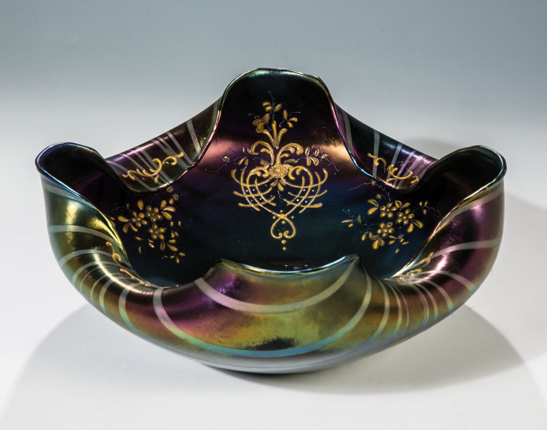 Schale: Schale Böhmen, um 1900 Dunkelviolettes Glas mit silbergelber, wellenförmig gekämmter Bandeinschmelzung. Stilisiert florale Reliefgoldmalerei. Vierpassig gelappte Mündung. Irisiert. D. 27 cm Schale