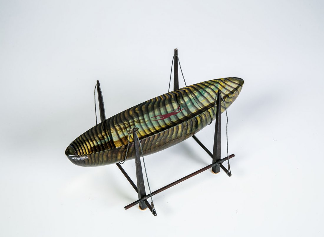 Objekt: Objekt Bertil Vallien (Entwurf), Kosta Boda Farbloser schiffchenförmiger Glasblock mit farbigen Aufschmelzungen. Zwischen den Schichten Kupfer- und fein gerissene Silberfolie. In Gravur bez.: KOSTA B