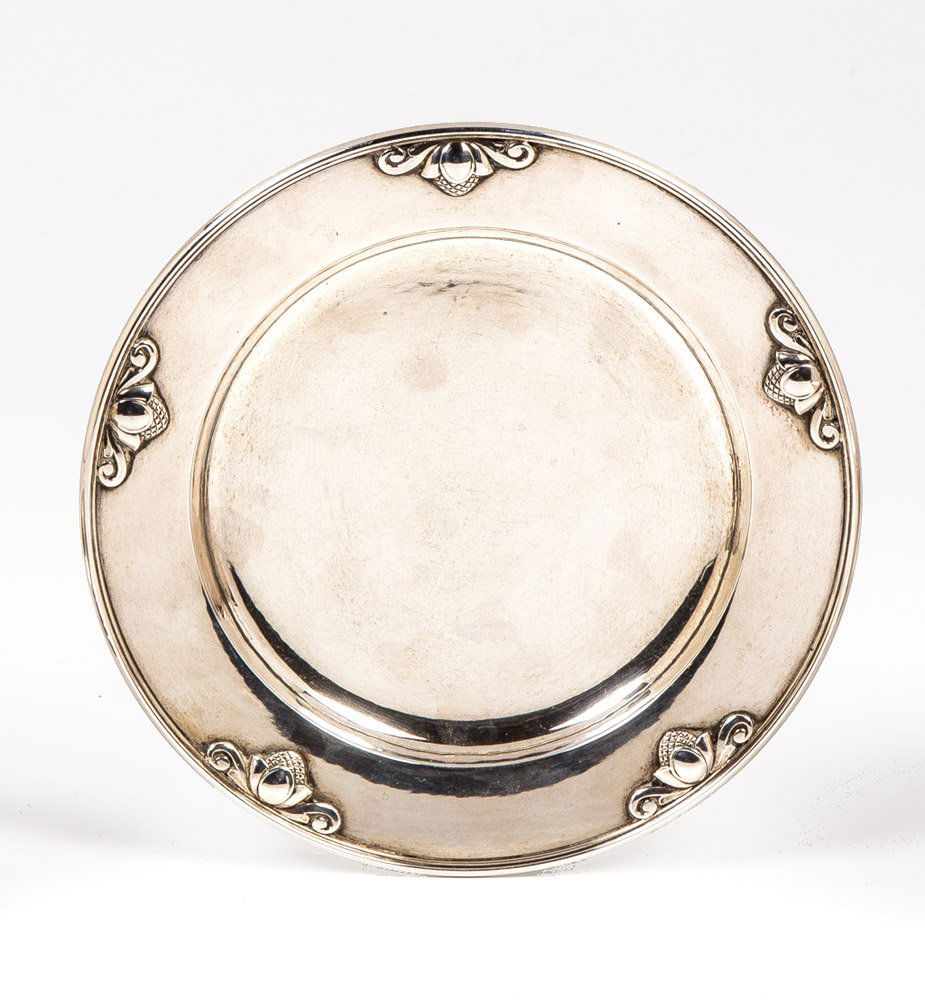 Presentoir: German: Presentoir Kopenhagen, Johan Rohde, 1915 (Entwurf), Firma Georg Jensen, 1930 (Ausführung) Silber. Rund. Profilierte Fahne mit reliefierten Pinienzapfen. Firmenmarke ''Georg Jensen'' (Oval mit