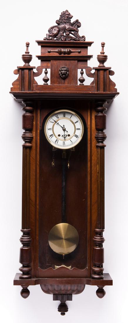 Late Empire Wall Hanging Clock: Late Empire period walnut hanging weight driven wall clock, carved case with half pilasters, large carved bracket and drop finials at base, top frieze with lion mask, pair finials and molded lion fini